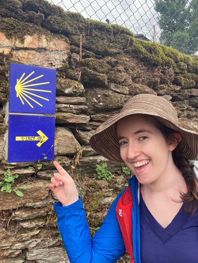 Traveler on the Camino de Santiago in Spain pointing towards a sign.