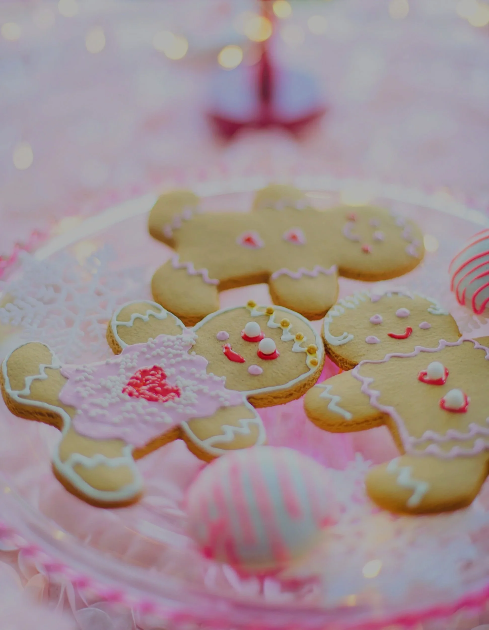 Colorful decorated cookies arranged on a pink surface with bokeh lights in the background.