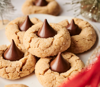 Chocolate thumbprint cookies with chocolate chunks on top, arranged on a white plate.
