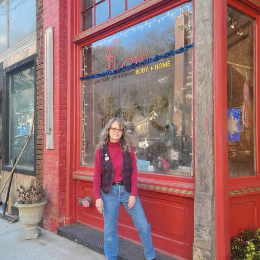 Woman standing outside a storefront with large red-painted window in an urban area.