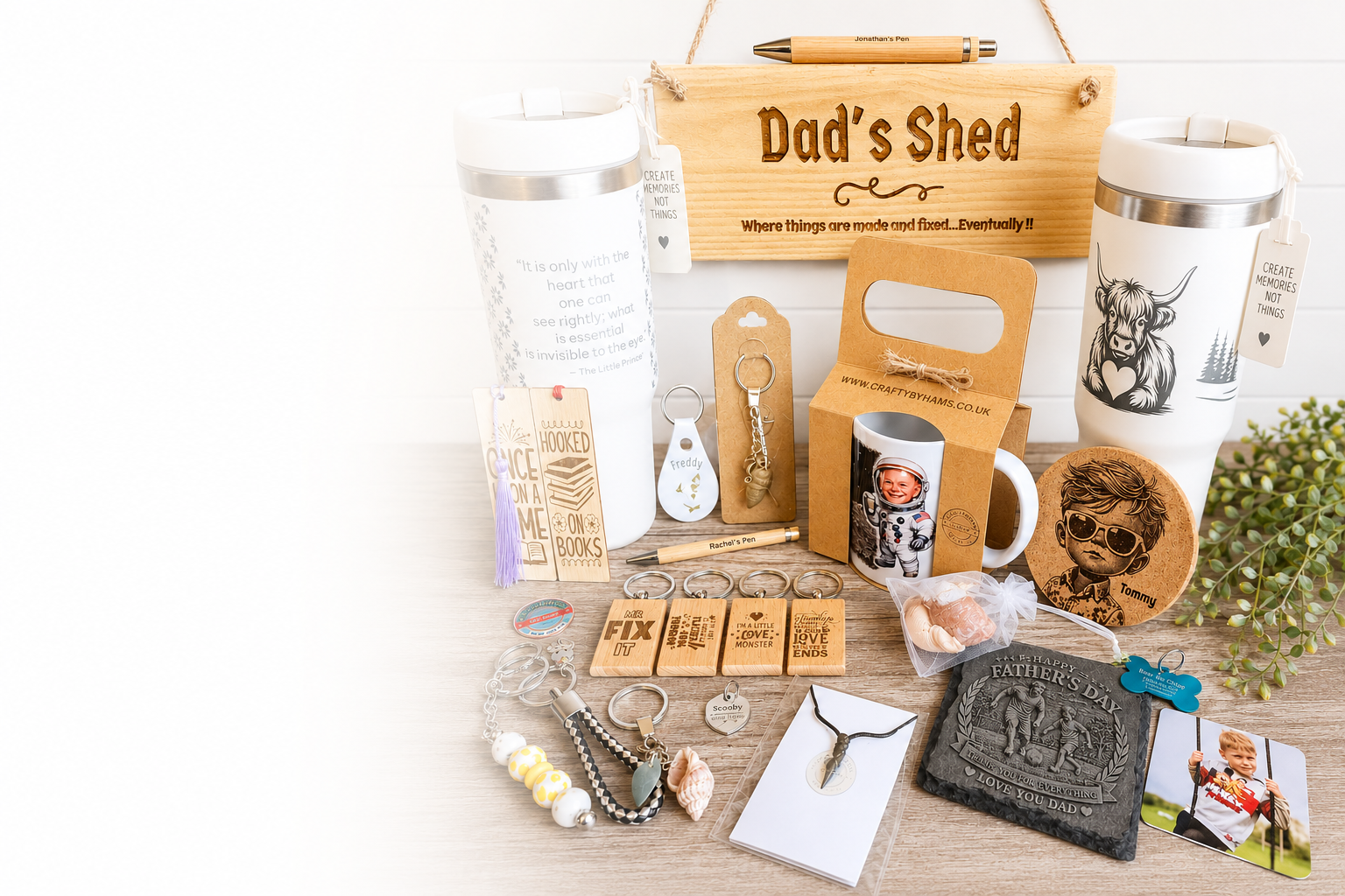 Collection of personalized gifts and accessories for Father's Day, including mugs with children's photos, keychains, a Father’s Day card, a wooden sign that reads "Dad's Shed" with a tagline, travel mugs, a necklace, a shell, and a small bag with a message.