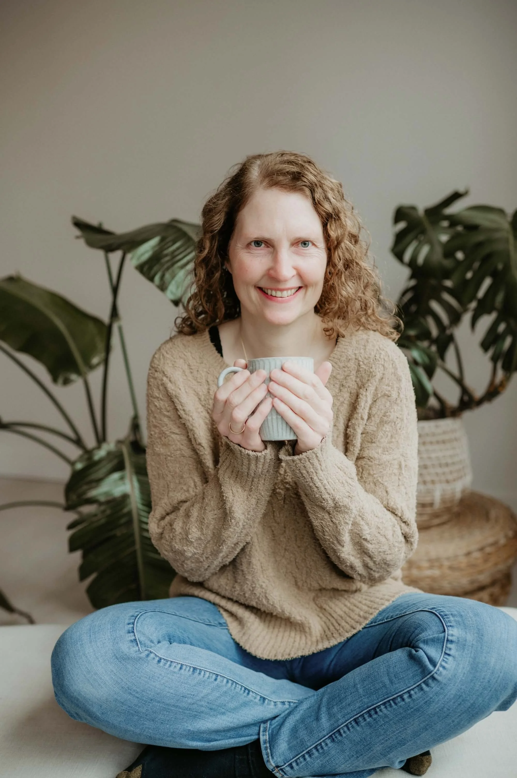 Margarita Durham smiling warmly with a cup of tea, reflecting the calm and joy she found through her own wellness journey.