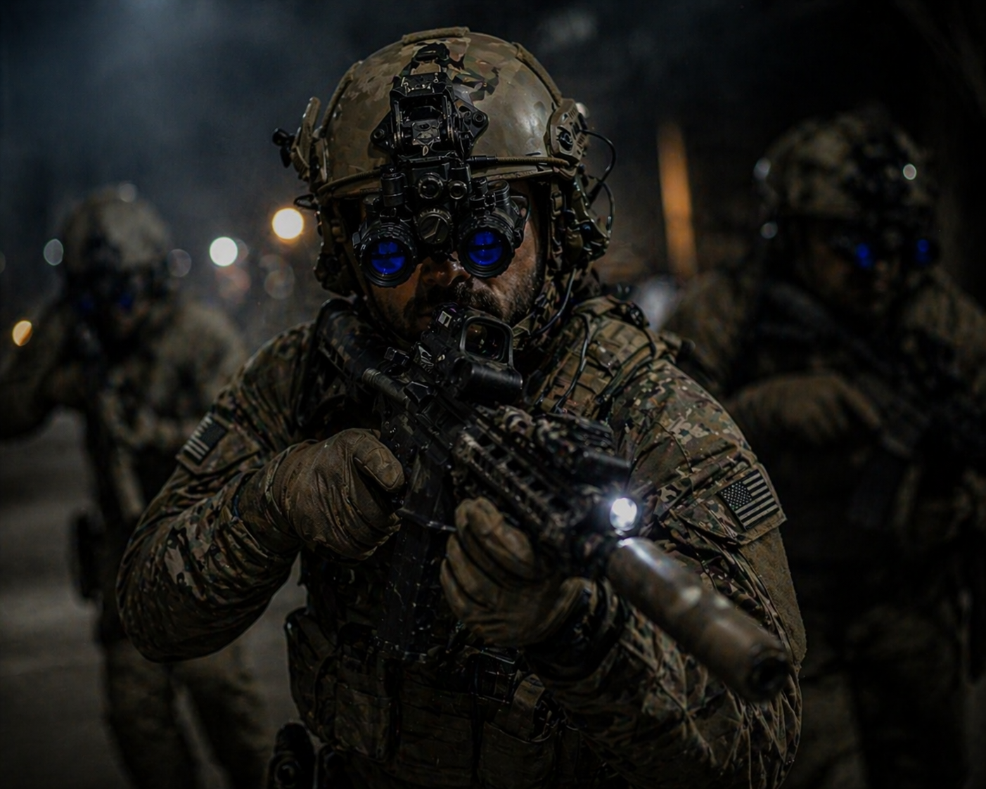 Soldier in camouflage uniform holding a gun with a flashlight, wearing night vision goggles, with other soldiers in similar gear in the background.