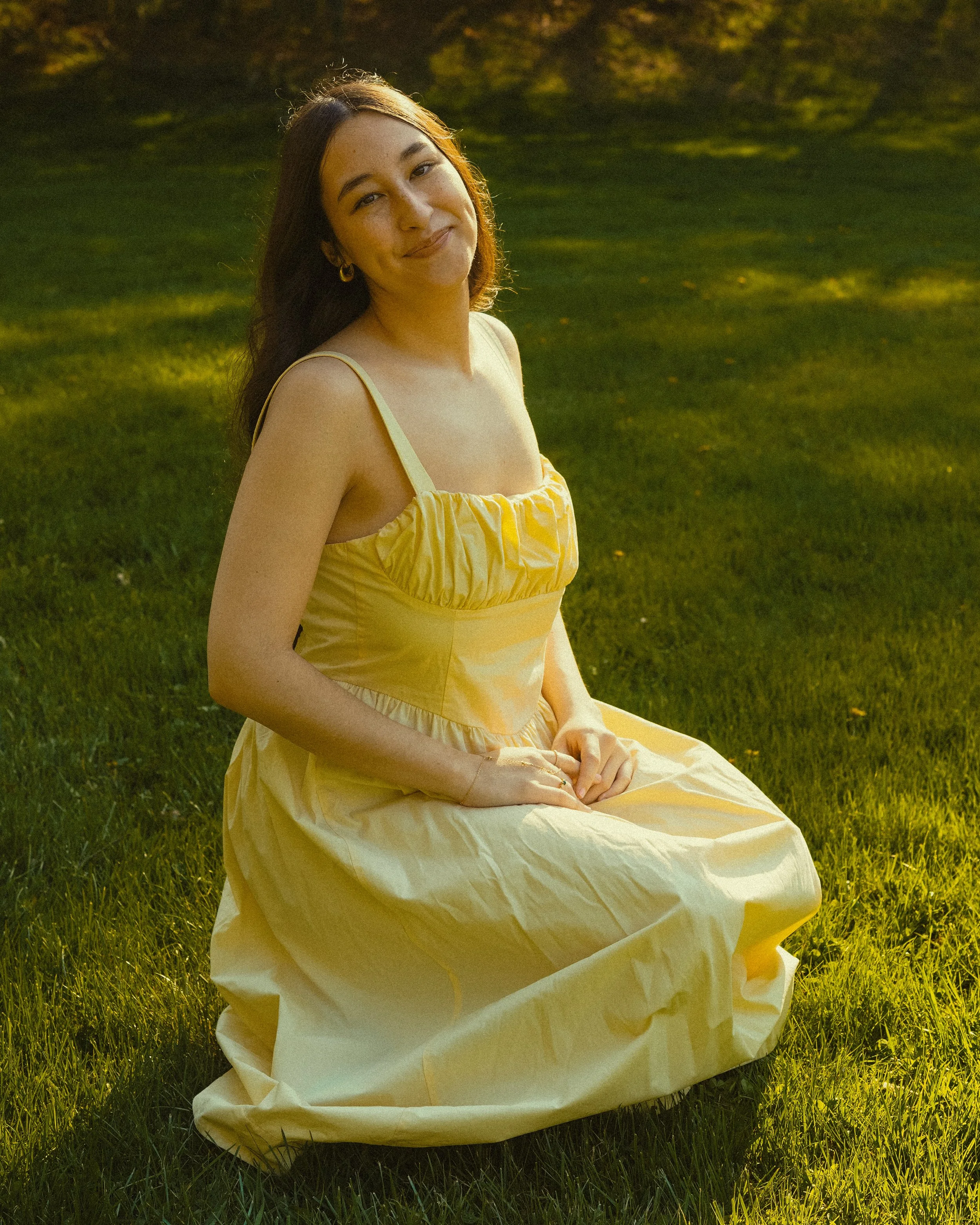 girl in yellow dress kneeling in a grass field