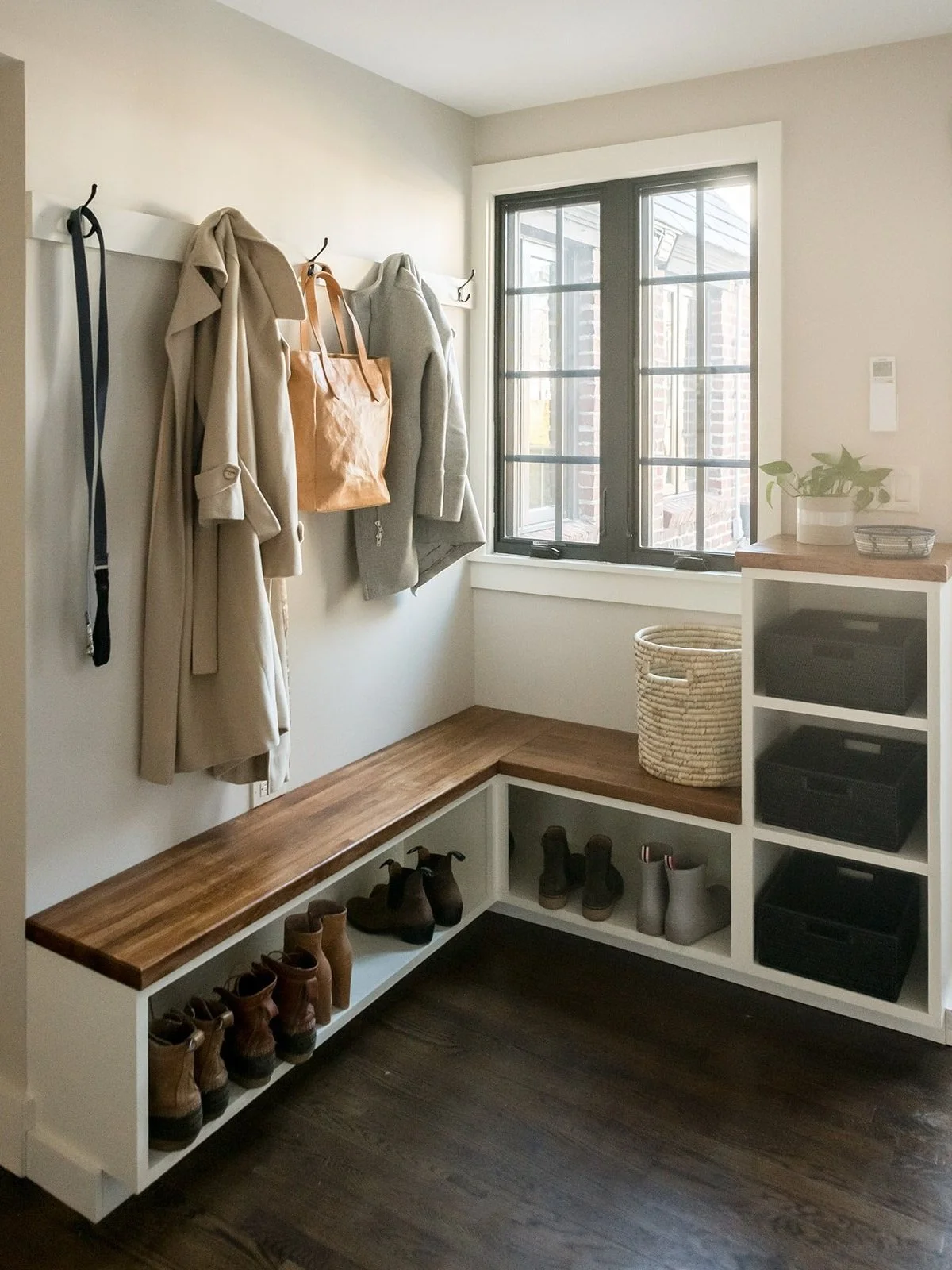 Entryway with coat hooks, a wooden bench, shoes, a window, and storage baskets.