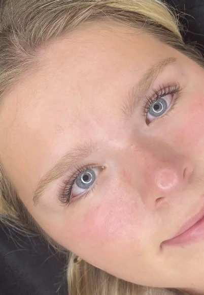 Close-up of a young woman's face with light skin, blonde hair, and blue eyes.