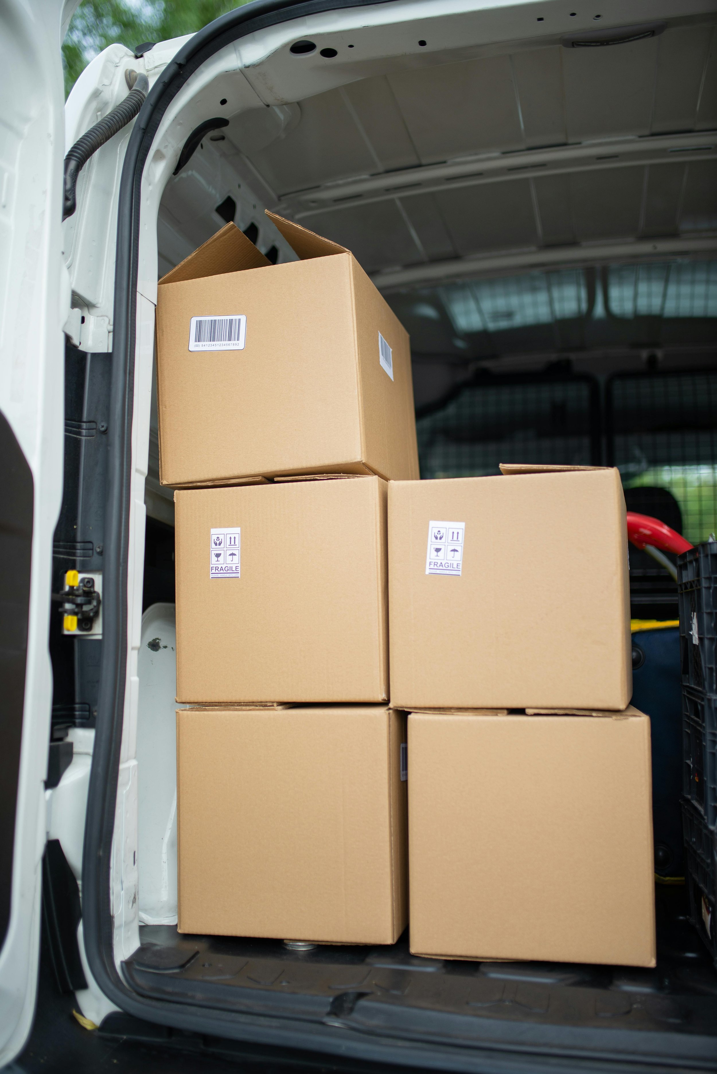 Several cardboard boxes stacked inside the cargo area of a white delivery van.