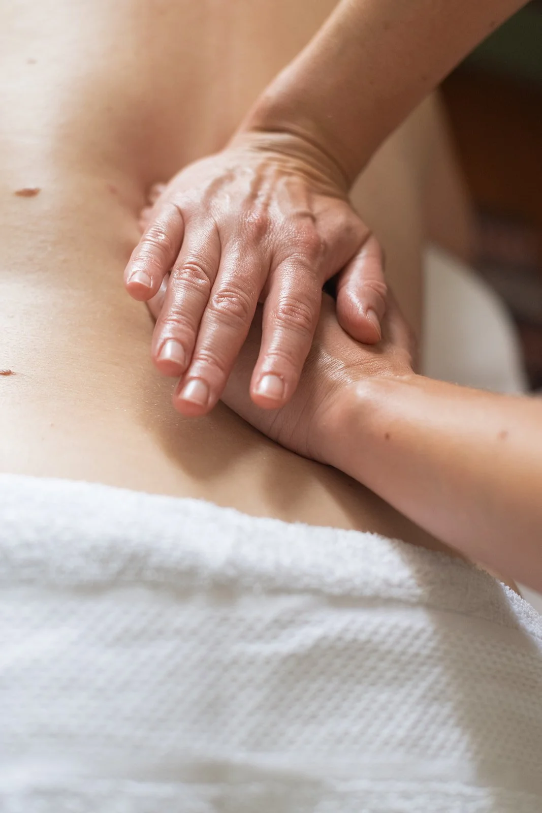 Close-up of a person giving a myotherapy massage for a sore back, with hands pressing along the spine, in a myotherapy clinic.