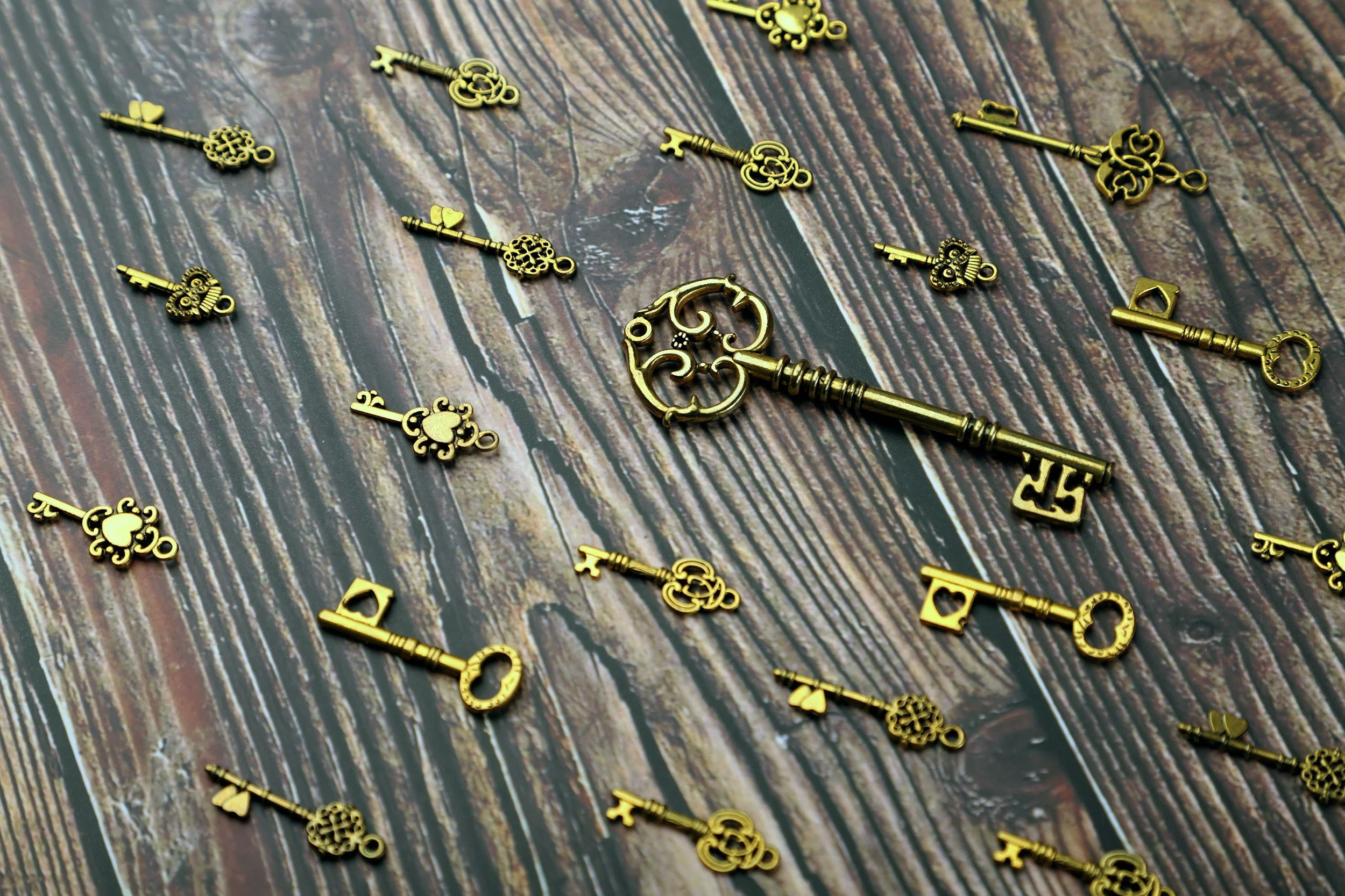 Golden decorative keys scattered on a wooden surface.