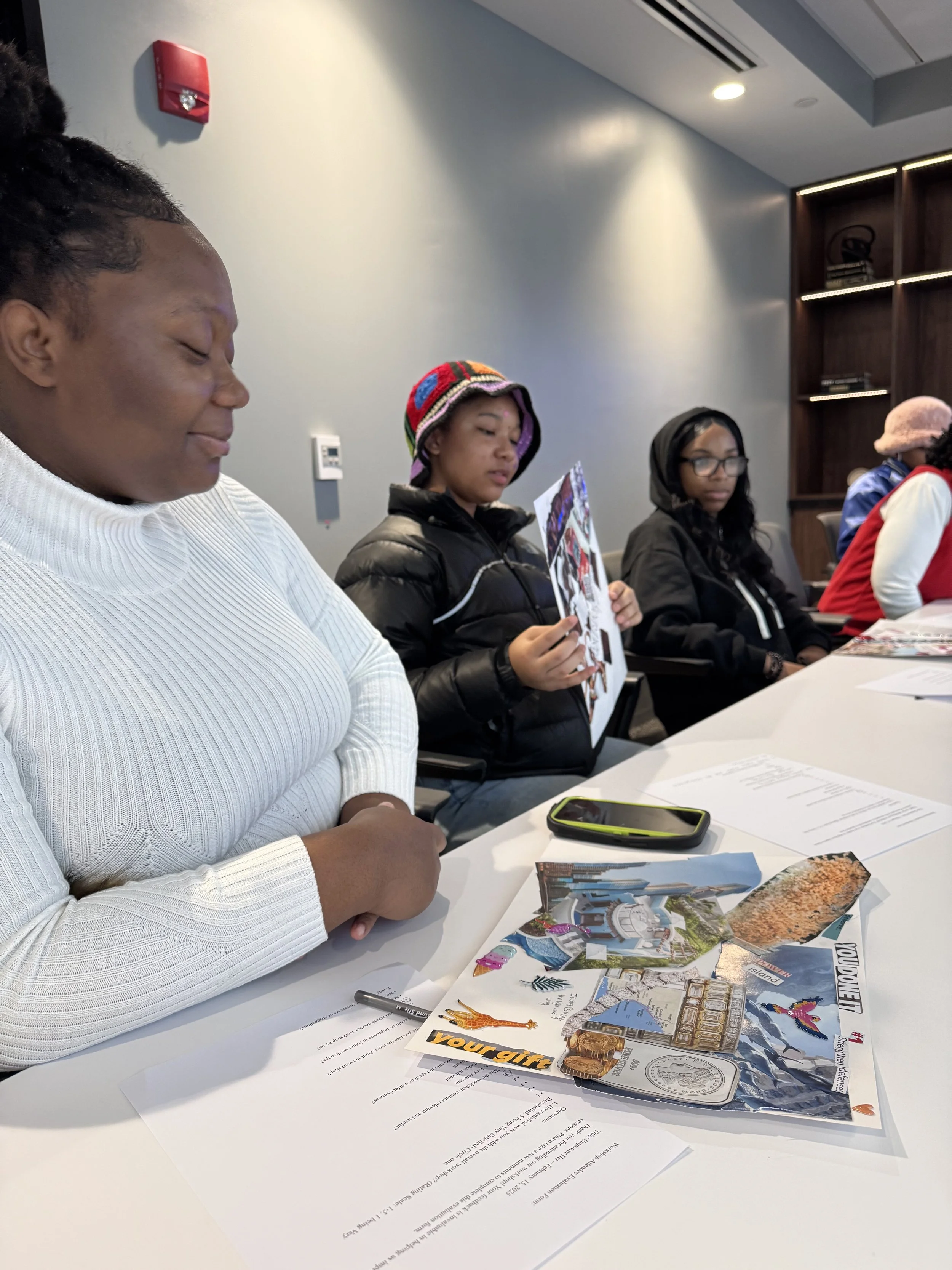 People sitting at a table, looking at pamphlets and brochures, with papers and a pen on the table in front of them.