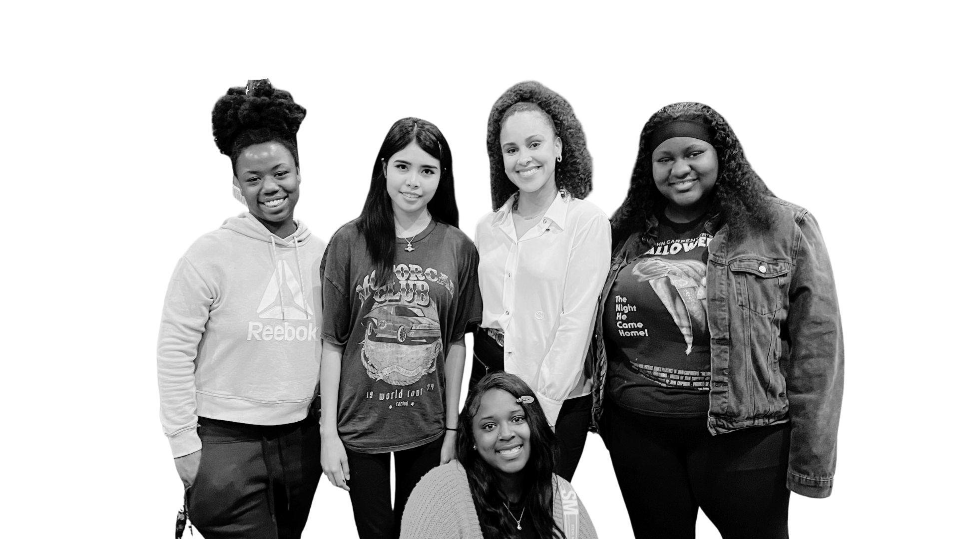 Group of five diverse women smiling and posing together, with two women seated in front, against a black background.