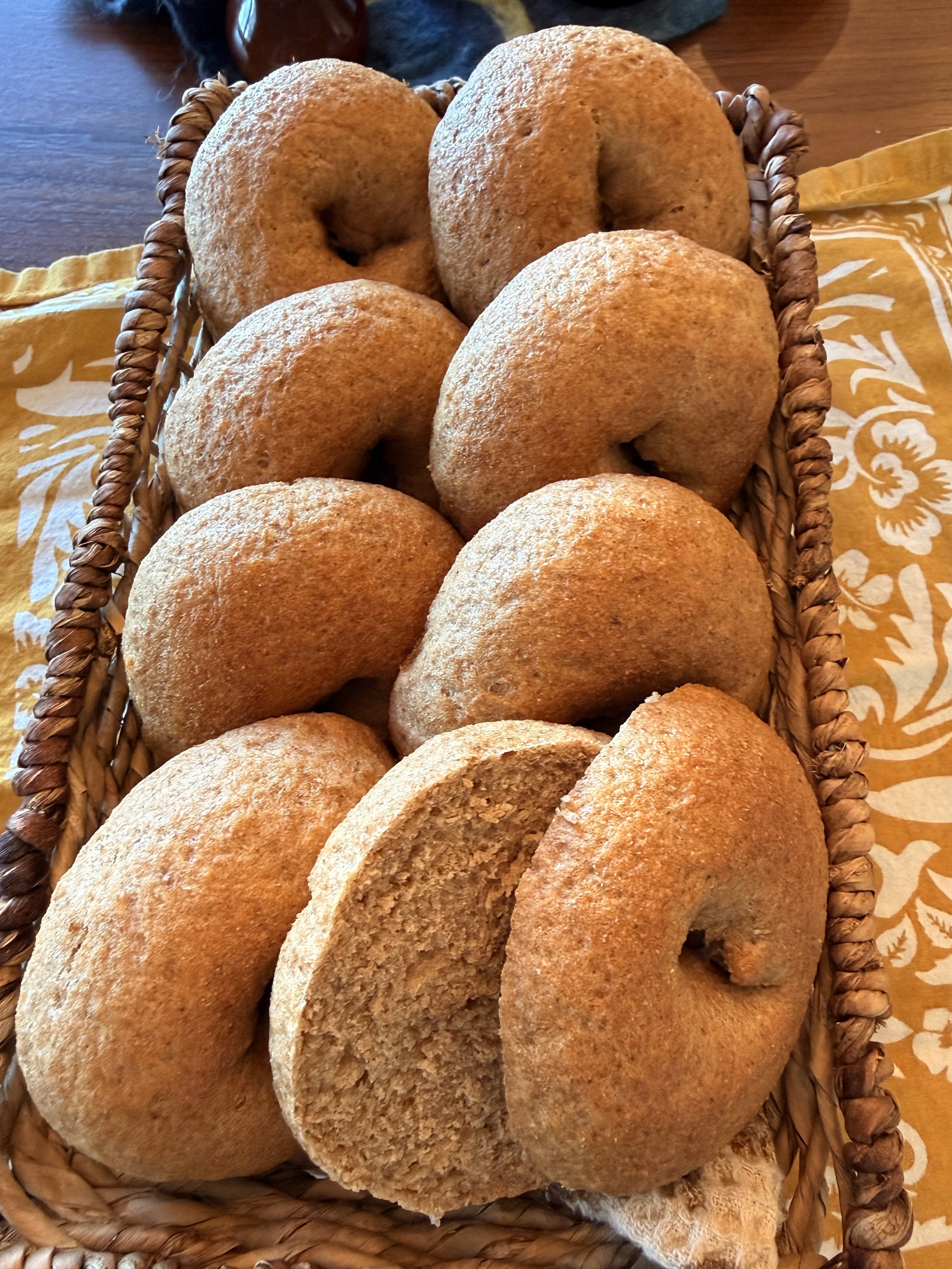 Basket filled with freshly baked bread rolls on a table with a yellow cloth.