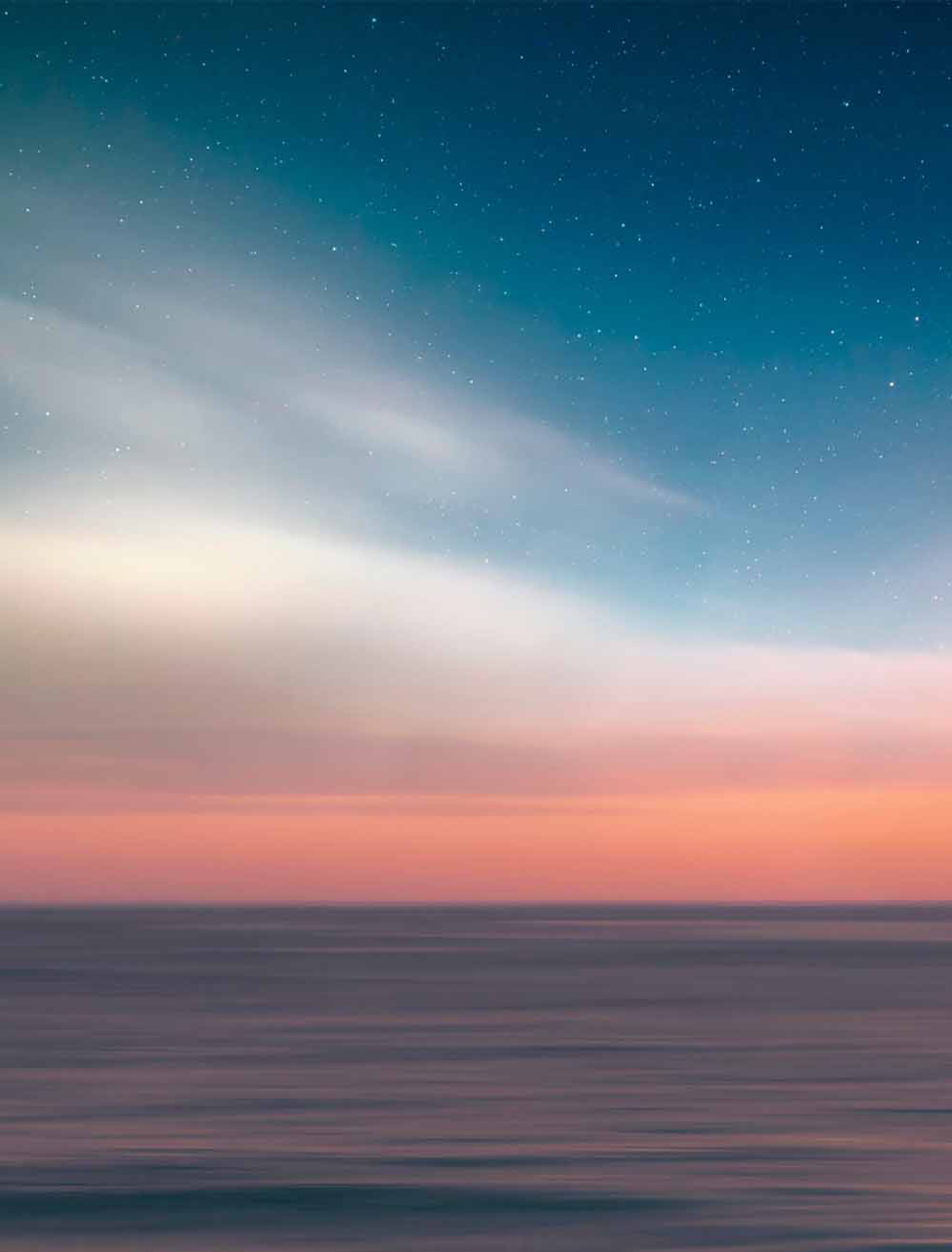PIcture of the sunset over the ocean with stars visible.