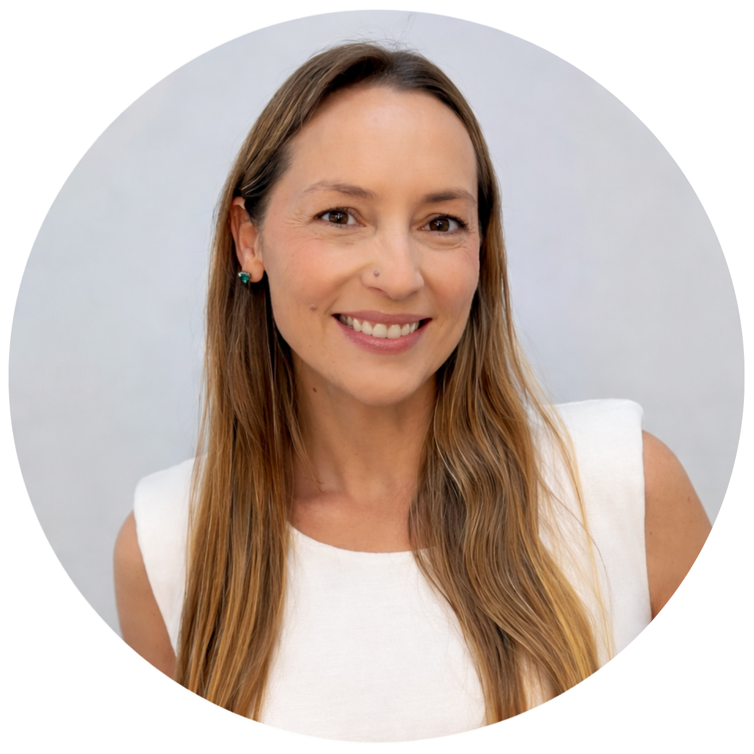 Vanesa Petitto. A woman with long, light brown hair wearing a white sleeveless top, smiling at the camera, with earrings and a small nose stud, against a plain light background.