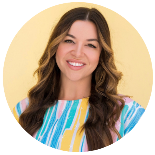 Claudia Veiga. Smiling woman with long wavy brown hair wearing a colorful striped shirt, standing in front of a yellow background.