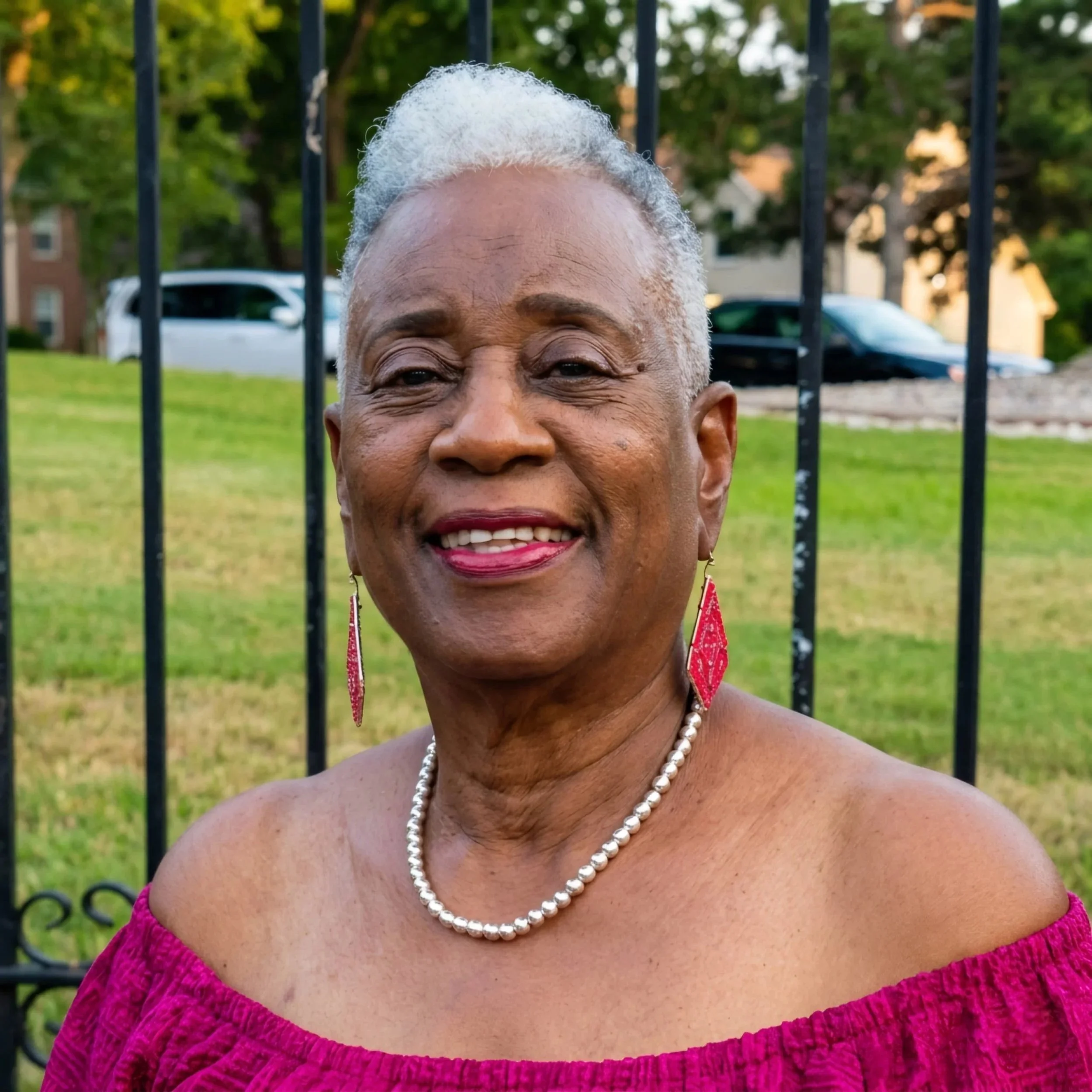 A smiling Black woman with curly hair styled in an updo, wearing earrings and a dark blazer against a neutral background.