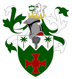 A coat of arms featuring a shield with a red cross and palm trees, a gray elephant's head, and a white lion holding an open book, surrounded by green decorative leaves.