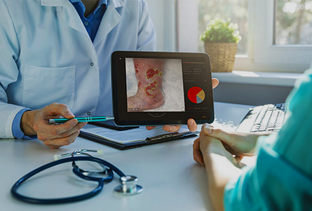 Clinician showing a patient an image of a foot ulcer on a tablet during a wound care consultation.