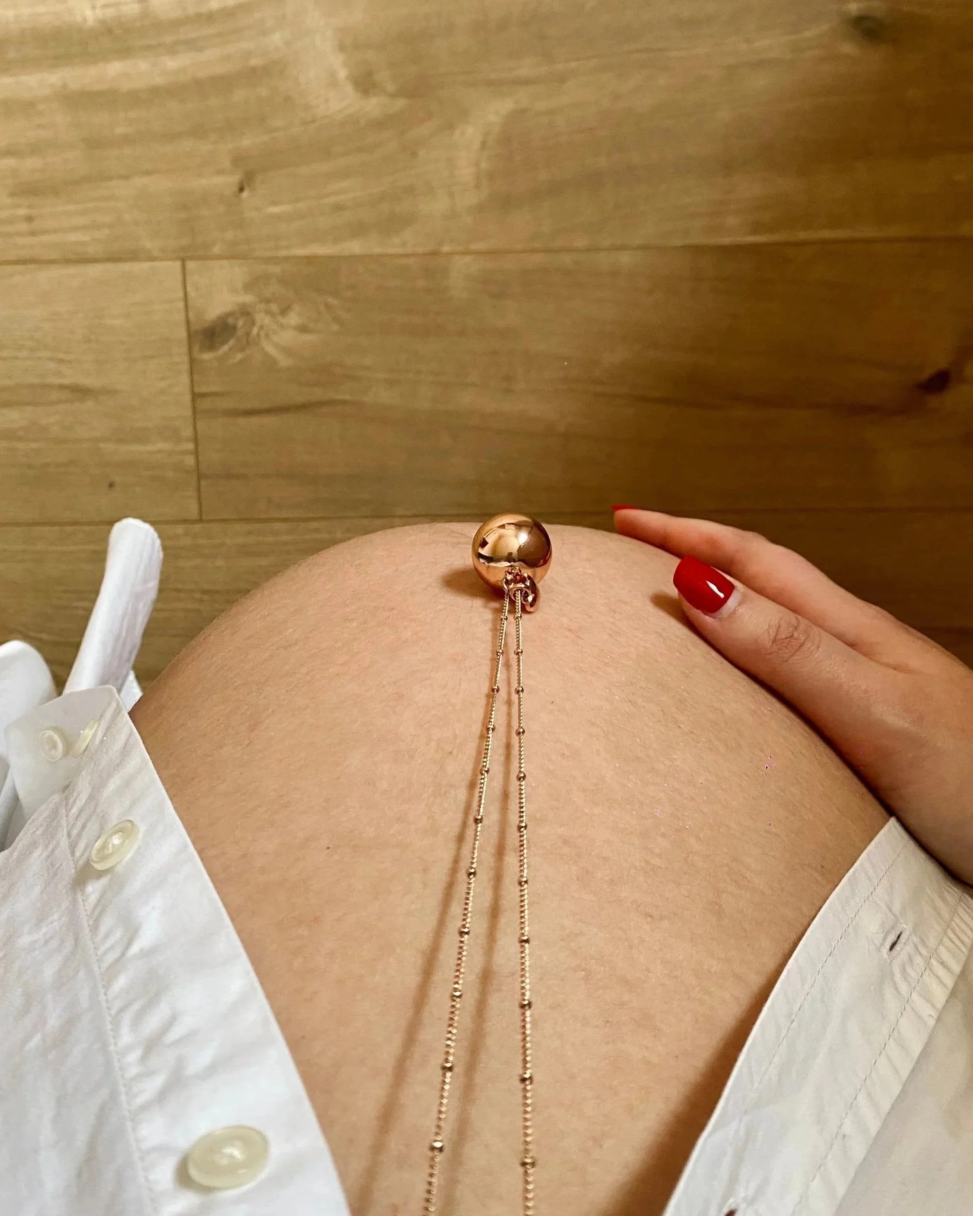 Ventre de femme enceinte vue du dessus avec un bola et une main sur le ventre