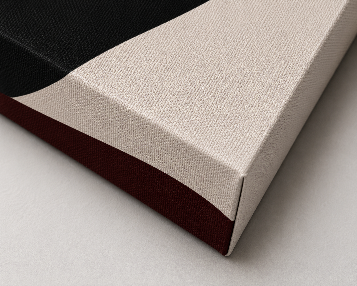 Close-up of a corner of a color-blocked canvas artwork, featuring black, beige, and maroon sections.