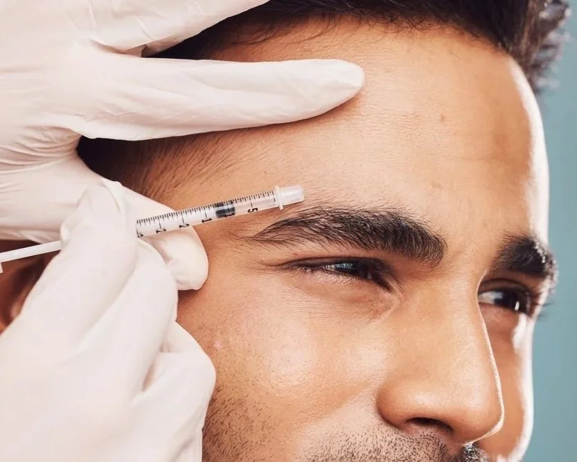 A person receiving Botox injections around the eyebrows from a medical professional wearing gloves.