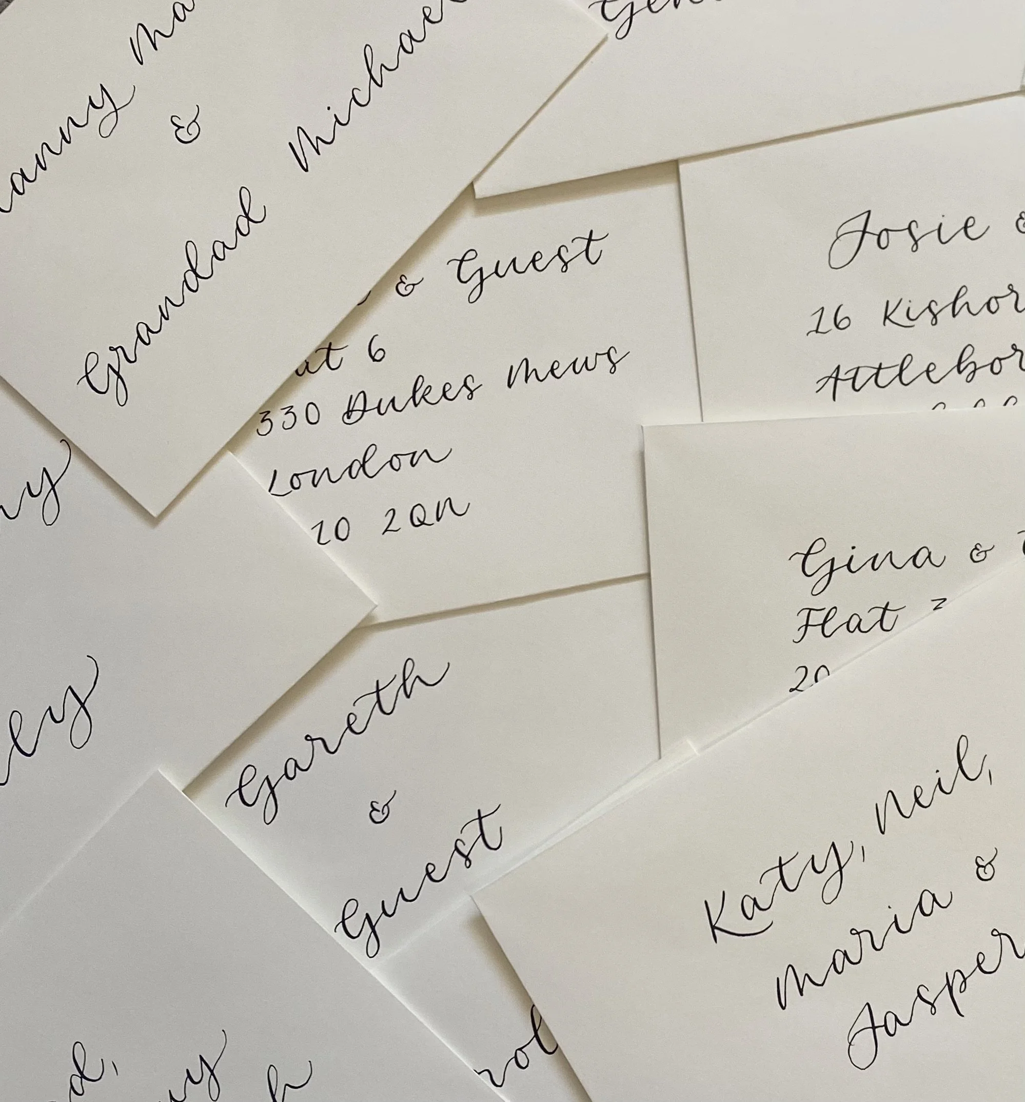 Multiple wedding invitations with elegant cursive calligraphy, featuring guest names and addresses.