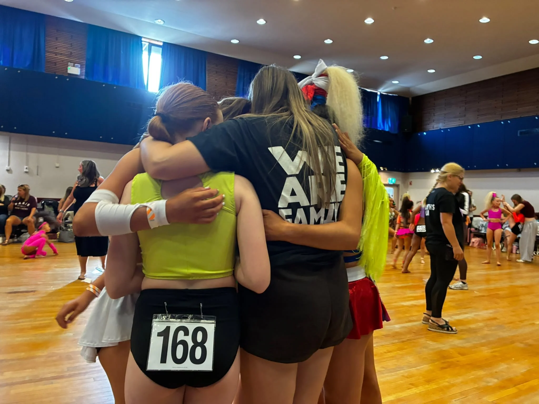 Group of dancers huddling in a crowded dance hall during a competition
