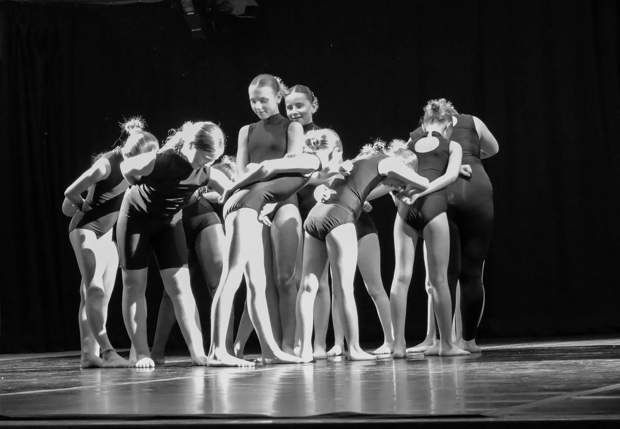 Black-and-white photo of young ballet dancers performing together on a theater stage.