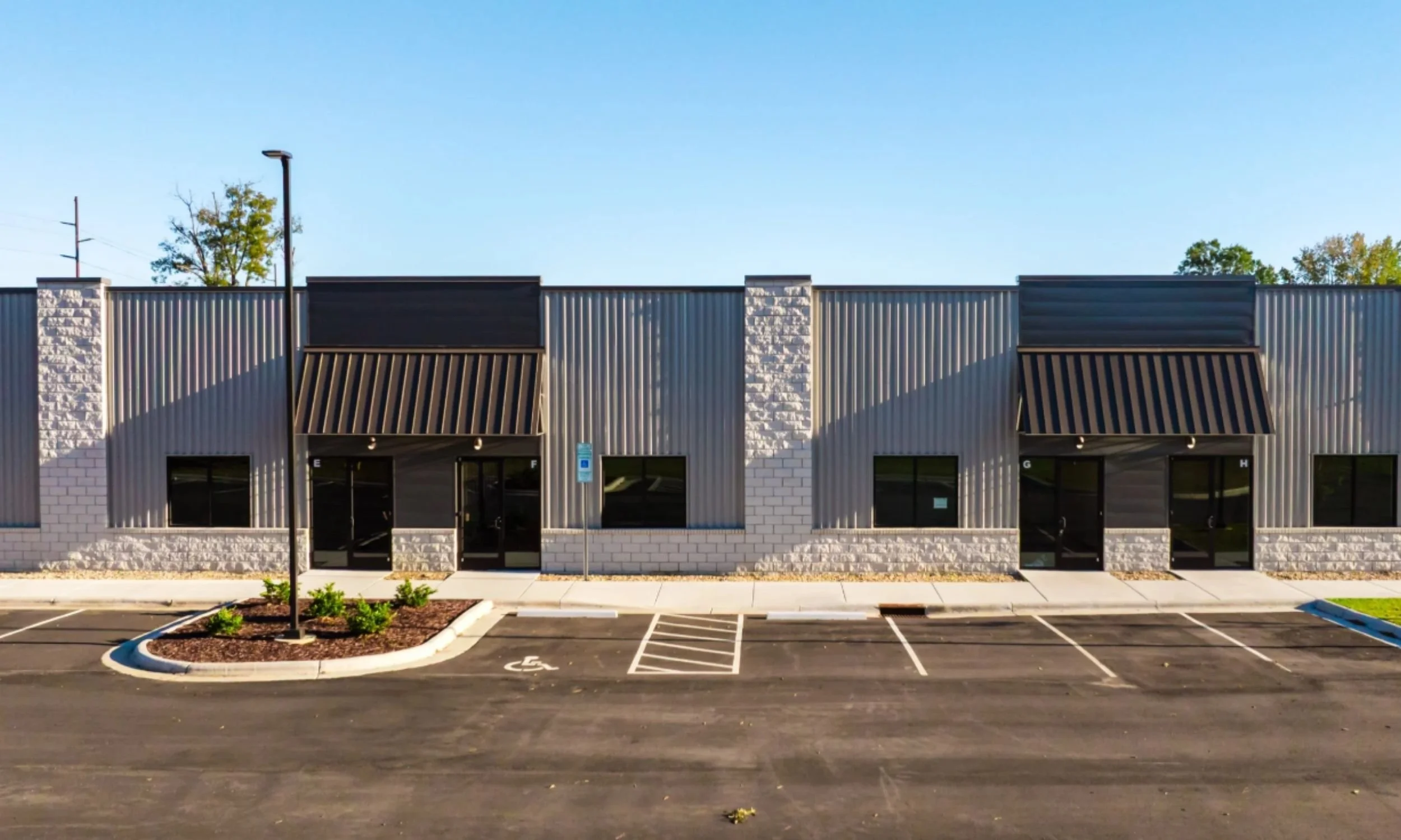 Commercial facade of Storage Works in Wilmington NC by LAT34 Architecture featuring stone accents, metal panels, awnings, and storefront entries.