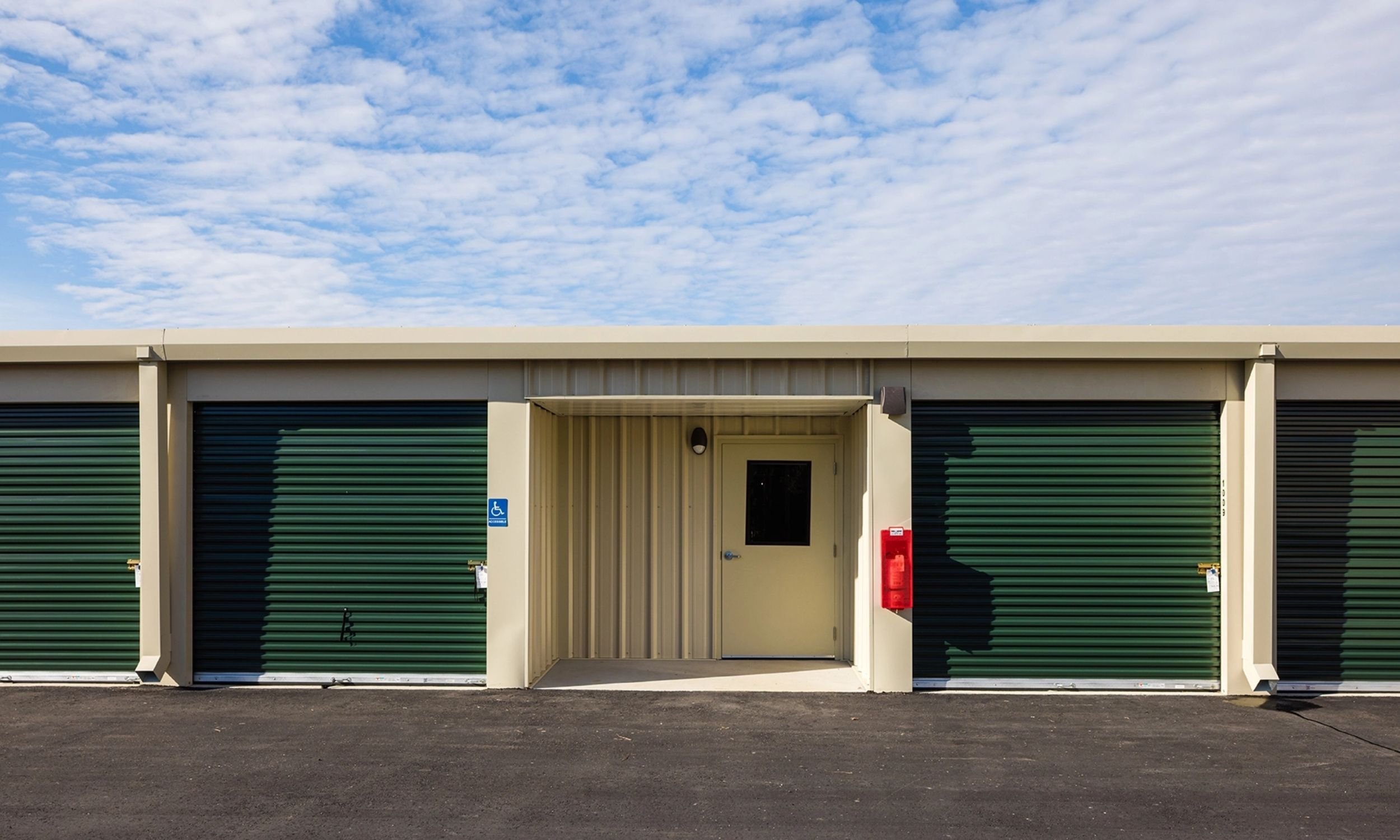Exterior of Pinnacle self-storage building designed by LAT34 Architecture with metal siding, green roll-up doors, and durable commercial construction.