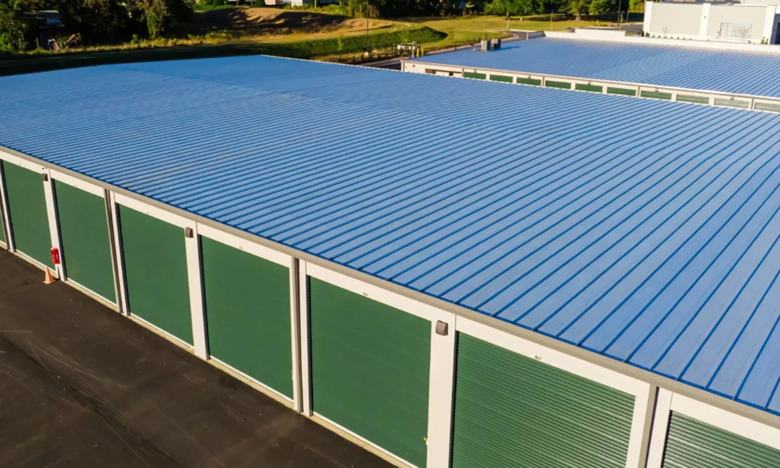 Storage Works commercial storage facility in Wilmington NC by LAT34 Architecture featuring metal roofing, green roll-up doors, and drive-up storage access.