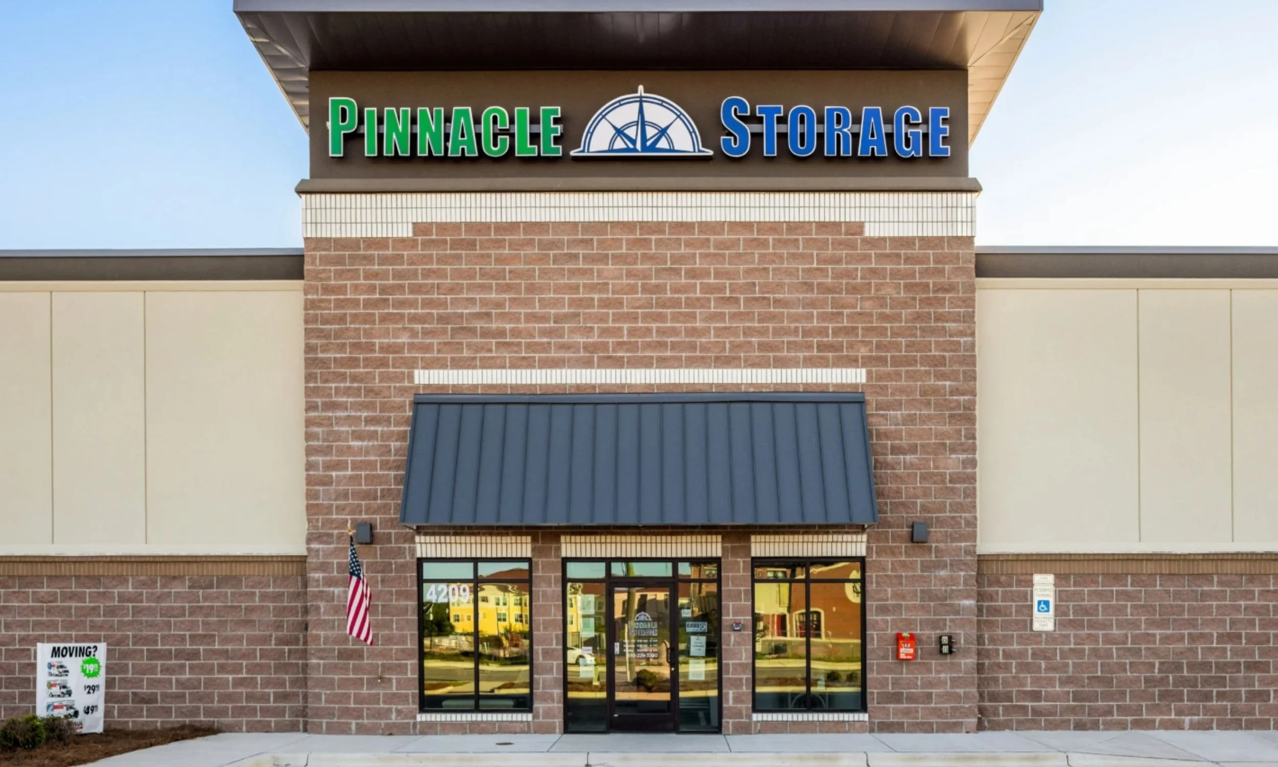 Office entry of Pinnacle Commercial Project in Wilmington NC designed by LAT34 Architecture with brick exterior, storefront glass, and metal awning.