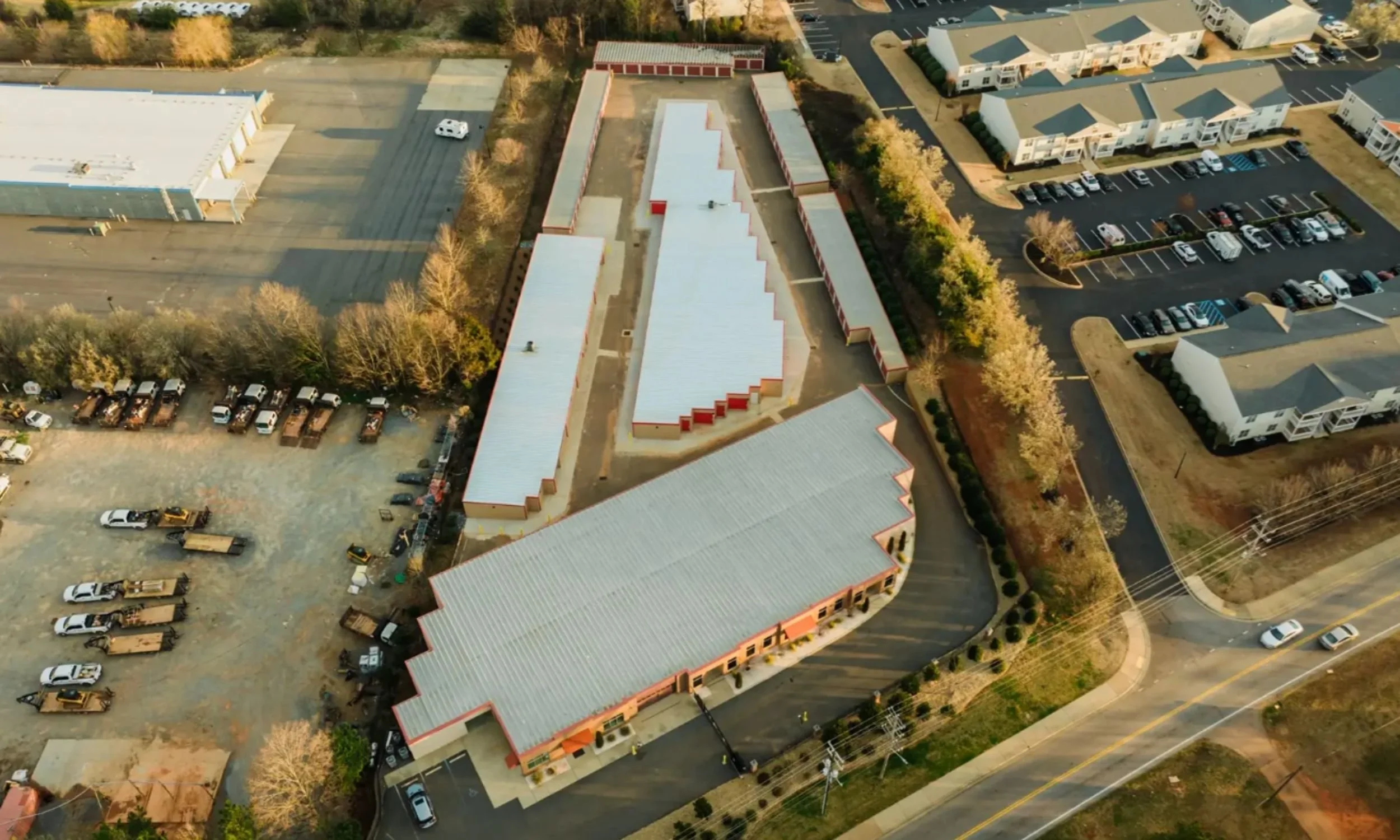 Drive-up storage building design in Wilmington NC by LAT34 Architecture with metal roofing, red unit doors, and commercial site planning.