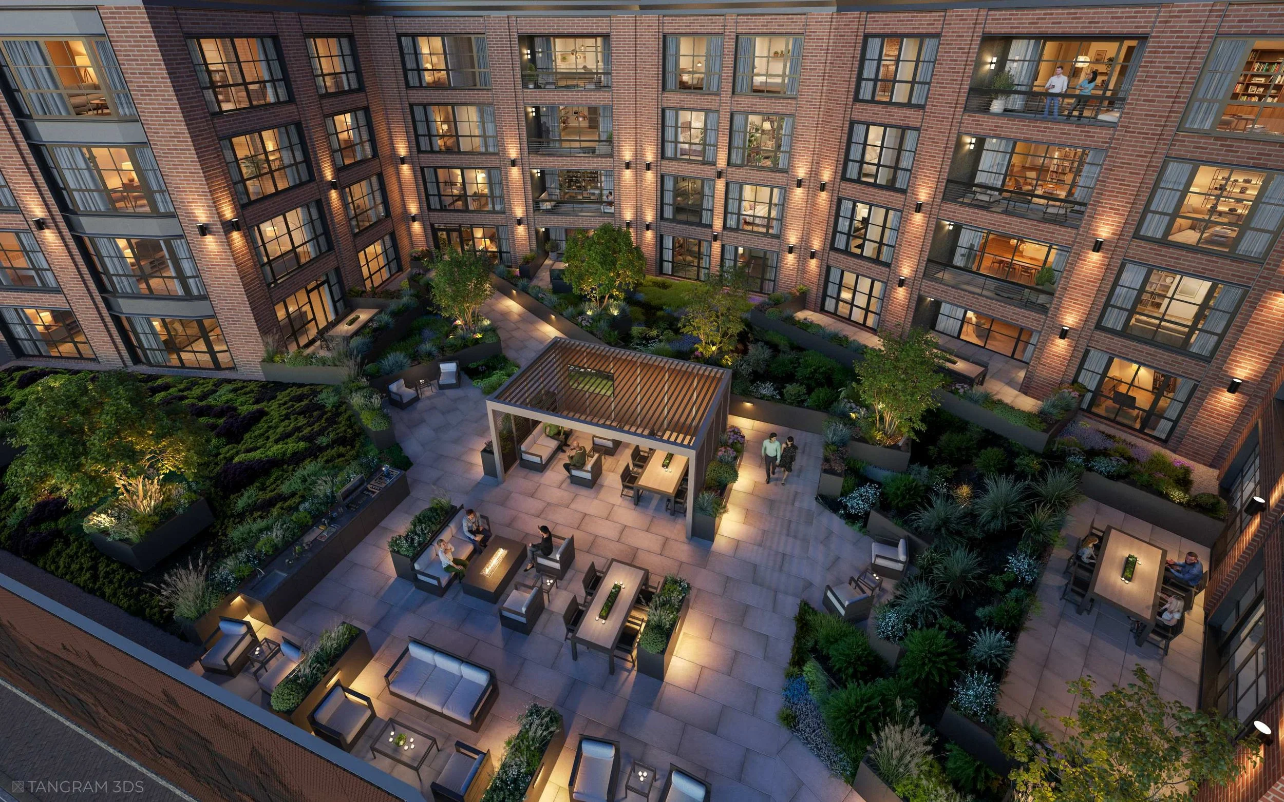 Night view of a modern apartment courtyard with outdoor seating, landscaped gardens, and illuminated walkways. Multiple floors of the building are visible with interior lights on and people inside and outside.