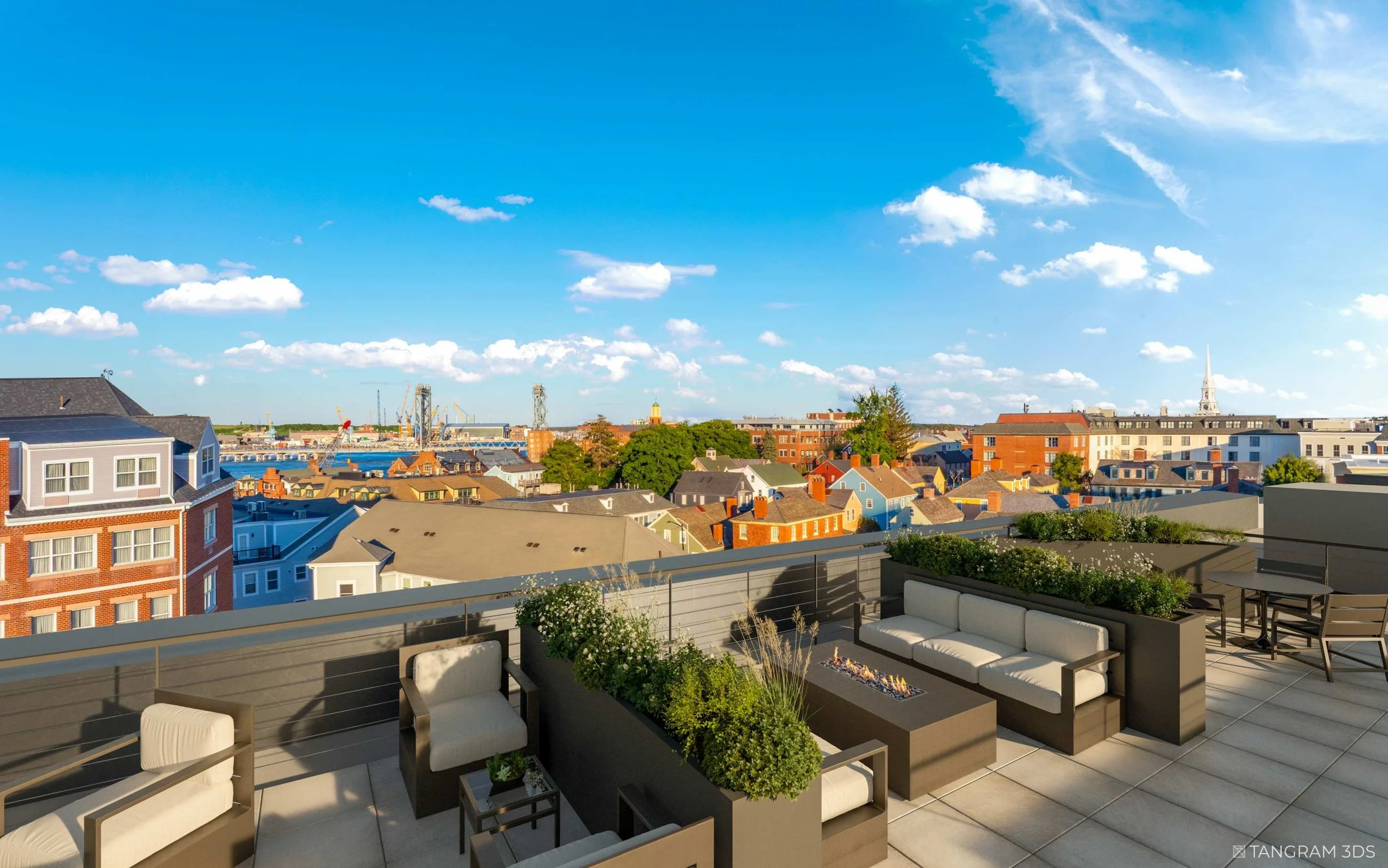 View from a balcony with modern outdoor furniture and potted plants overlooking a cityscape with colorful buildings, a river, cranes, and a church steeple under a partly cloudy sky.