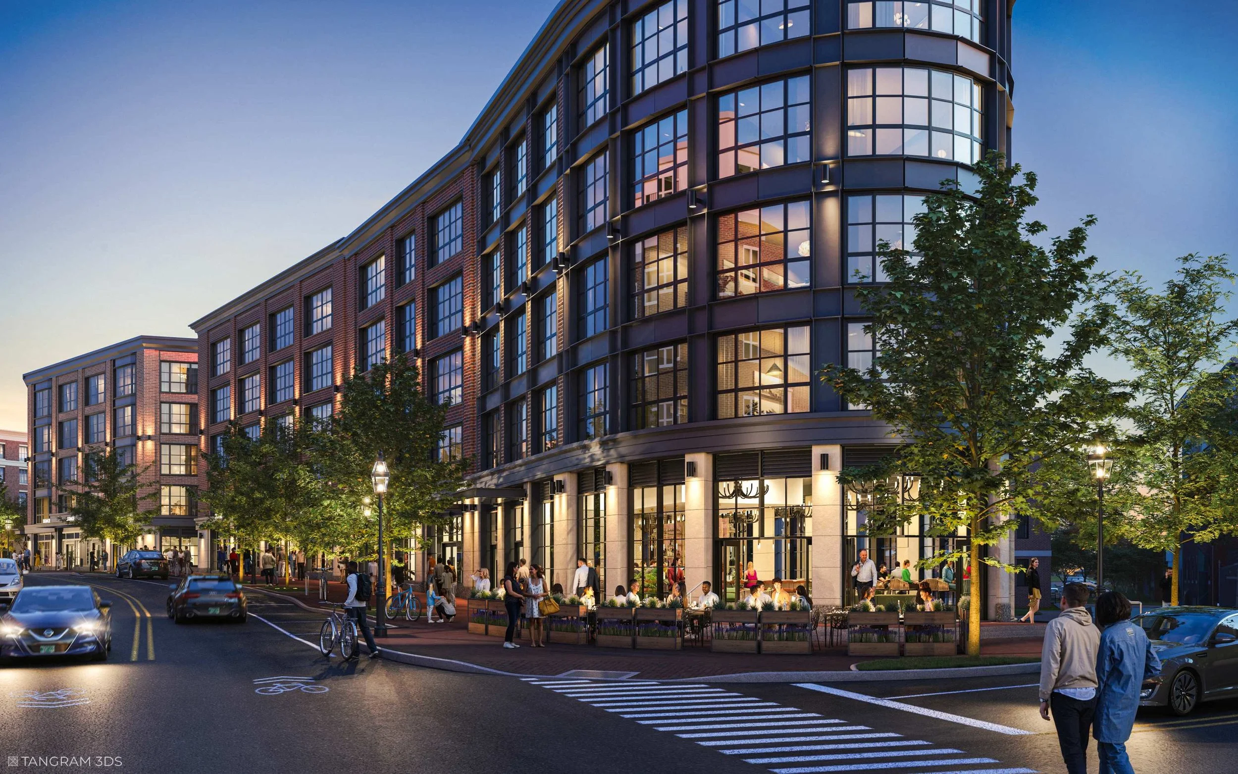 A modern multi-story building with large glass windows illuminated from inside, surrounded by trees and streetlights. People are walking on the sidewalk, and cars are on the street during dusk.