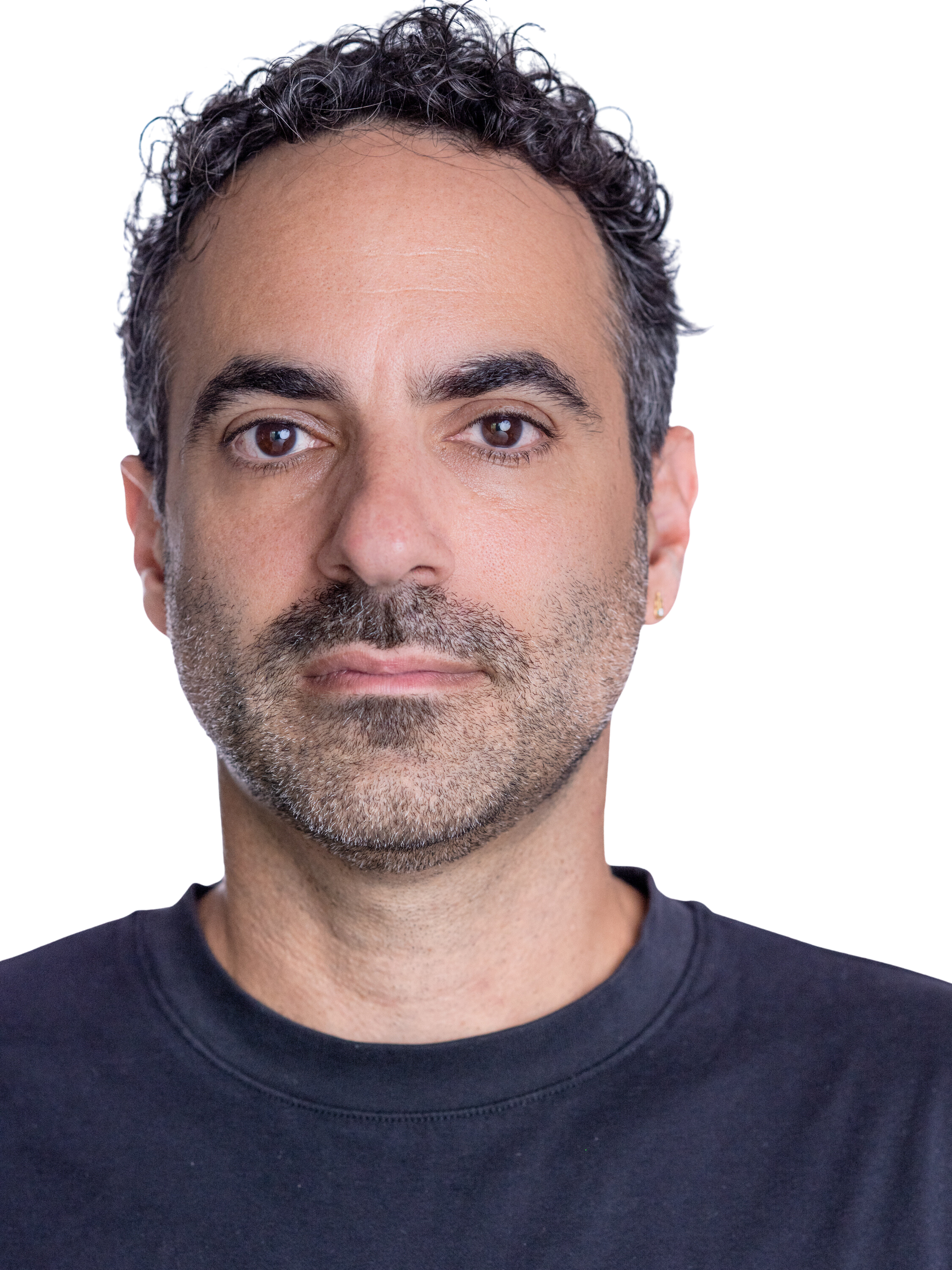 Close-up of a man with short curly dark hair, brown eyes, and a beard, wearing a black shirt, looking directly at the camera.