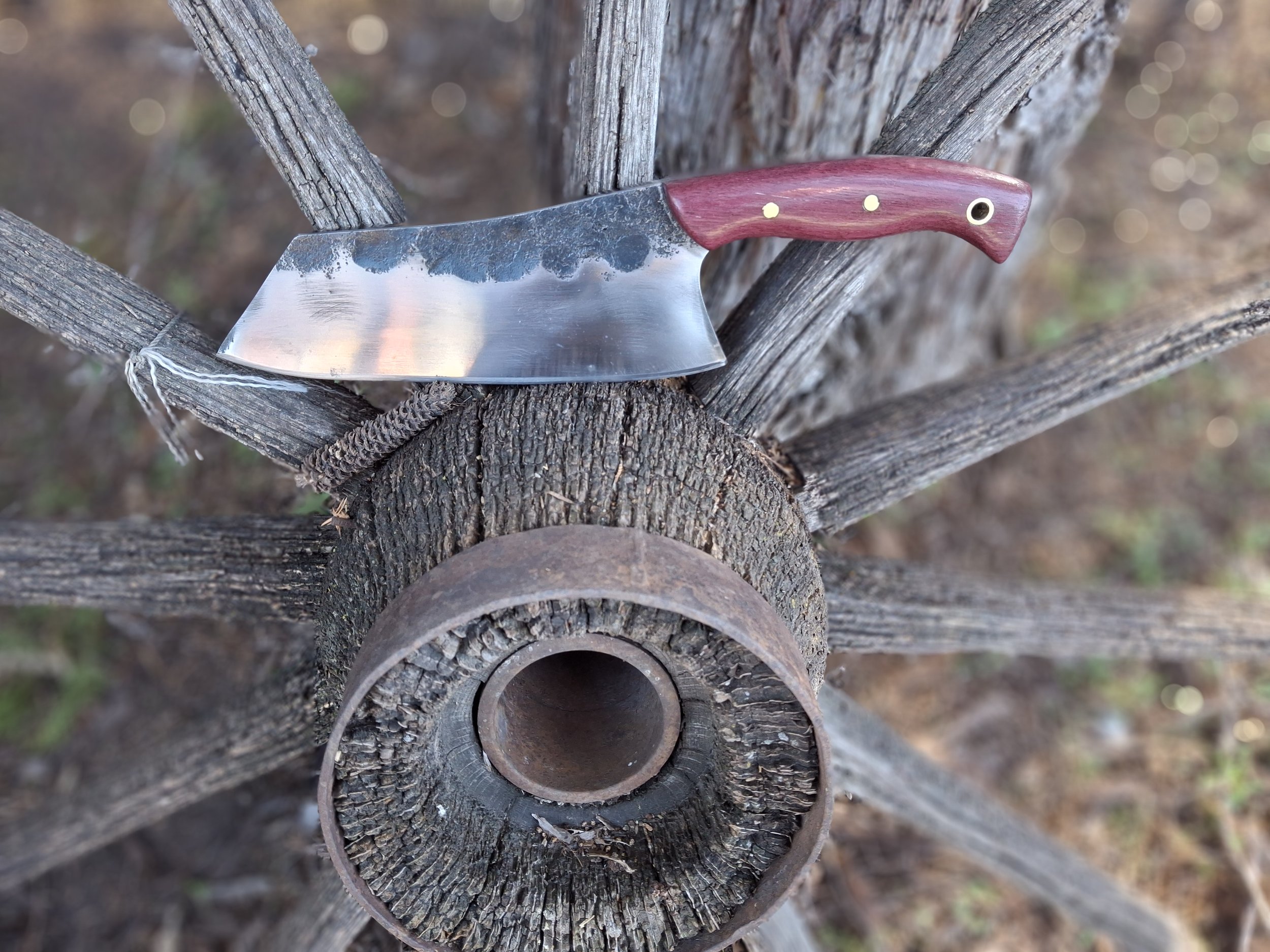 A cleaver sitting on an old wagon wheel.