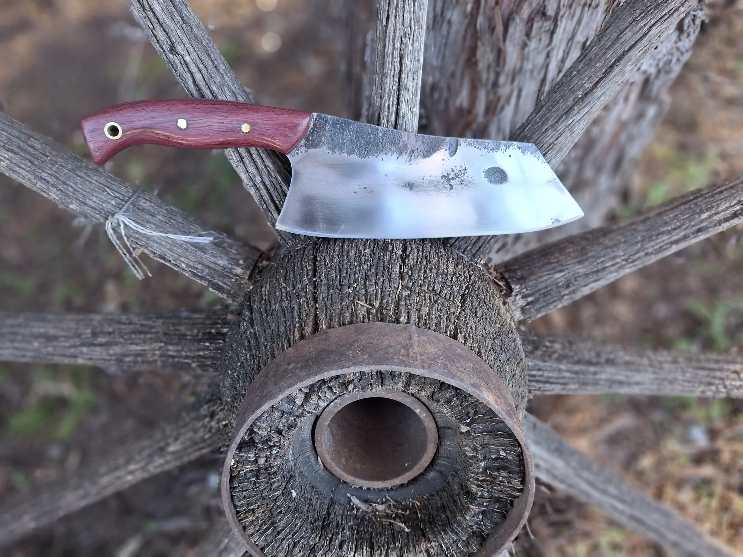 A cleaver sitting on an old wagon wheel.