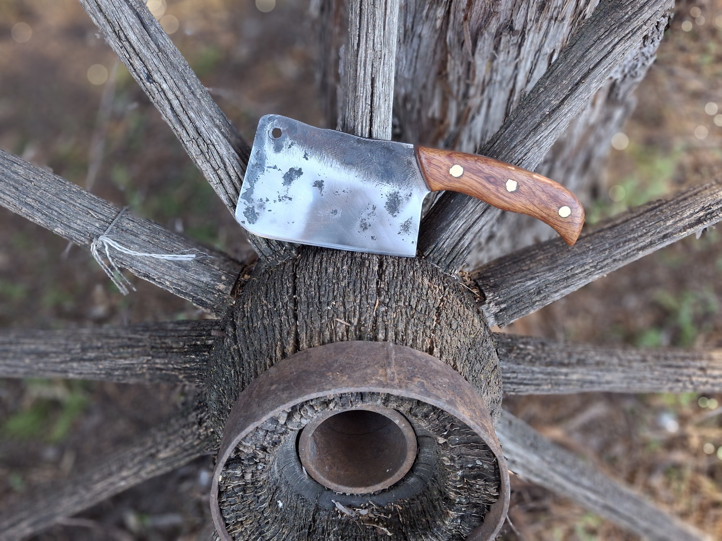A cleaver sitting on an old wagon wheel.