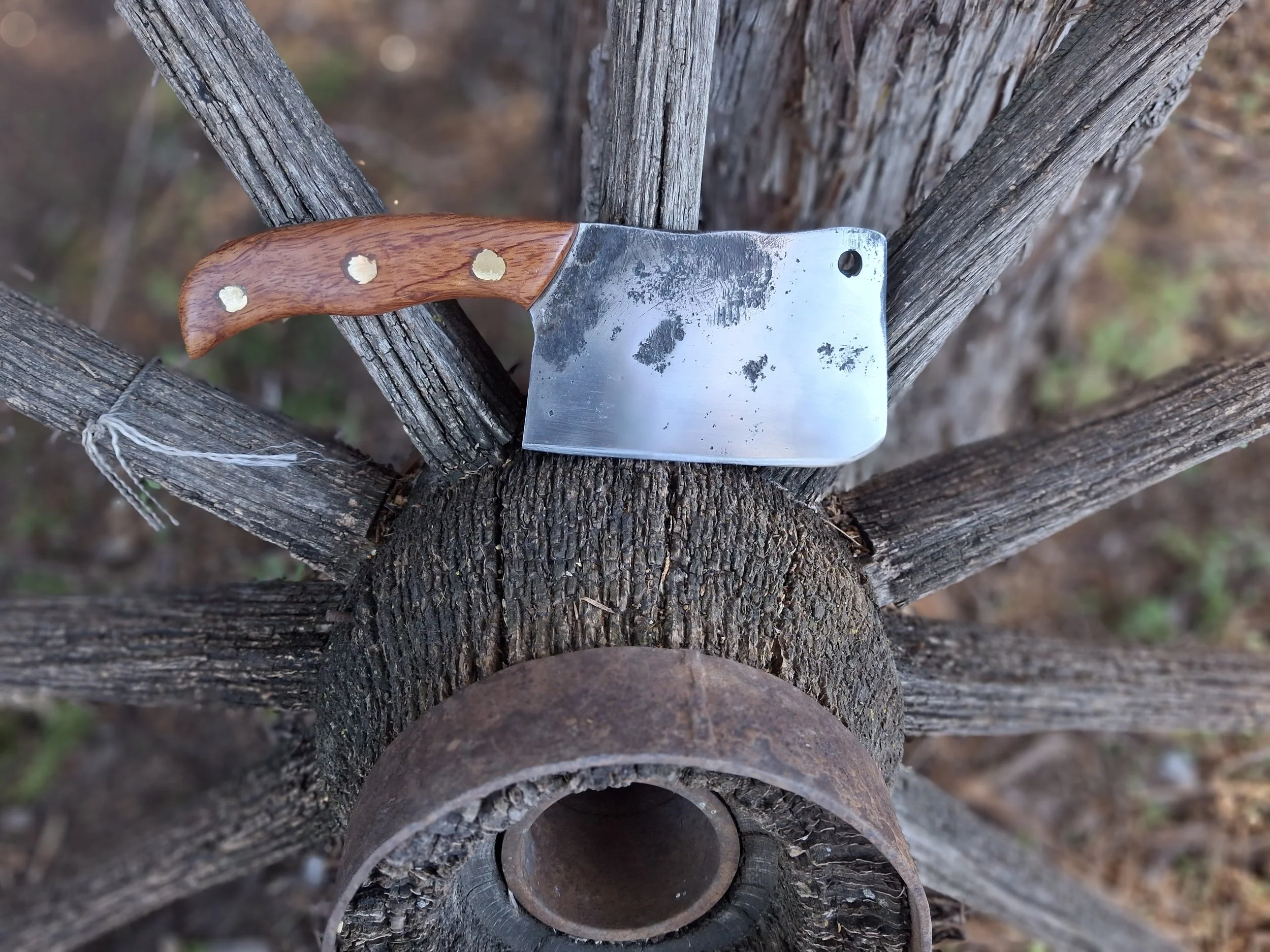 A cleaver sitting on an old wagon wheel.