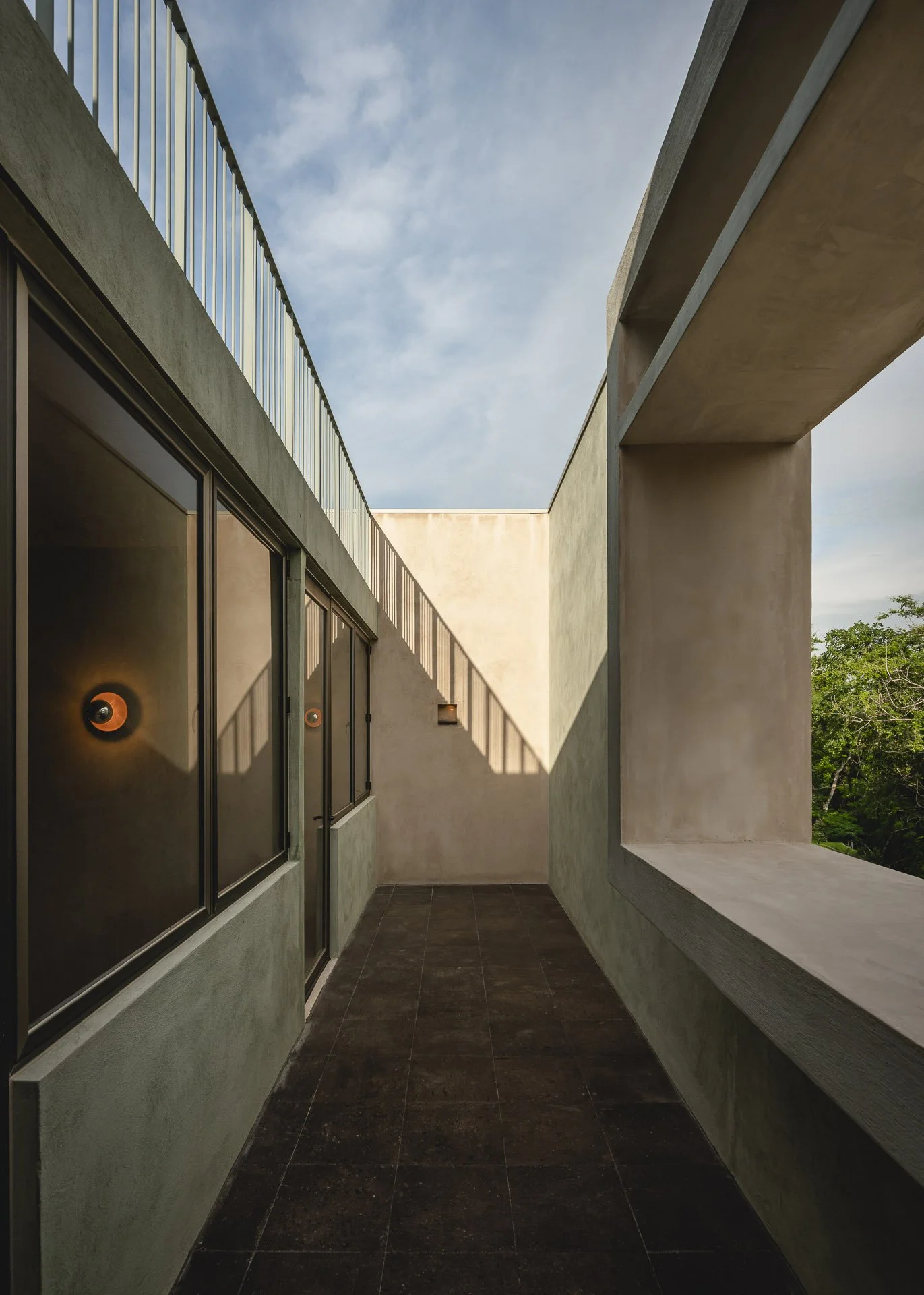 Detalle de acabados de alta gama en pasillo exterior residencial, obra de la constructora Ensemble en Yucatán.