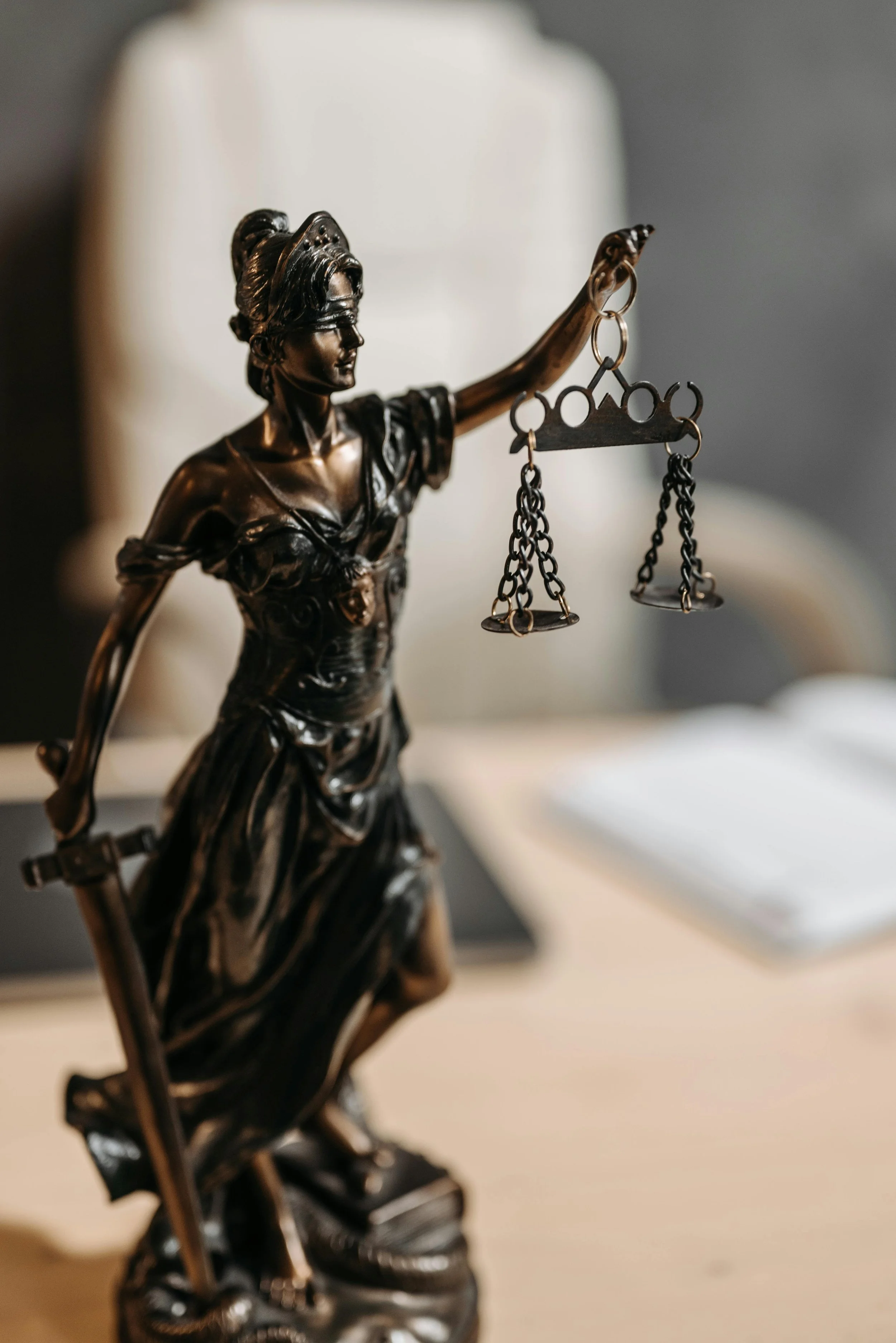 Close-up of a bronze statue of Lady Justice holding scales.