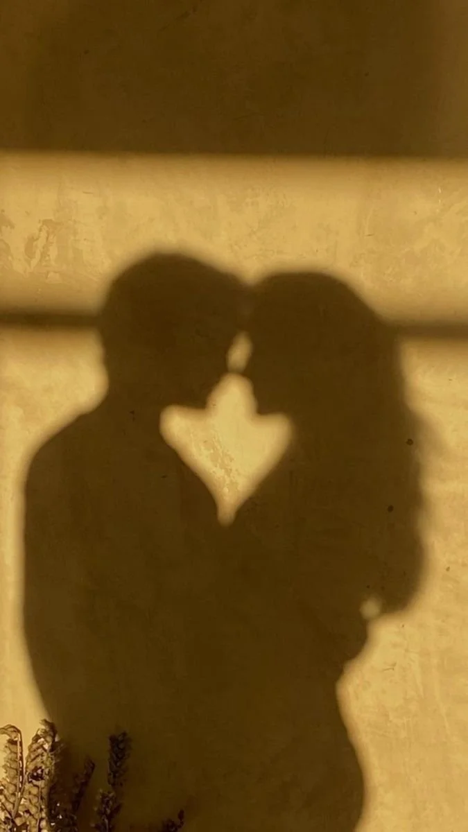 Shadow of a couple touching foreheads with a heart-shaped space between them.