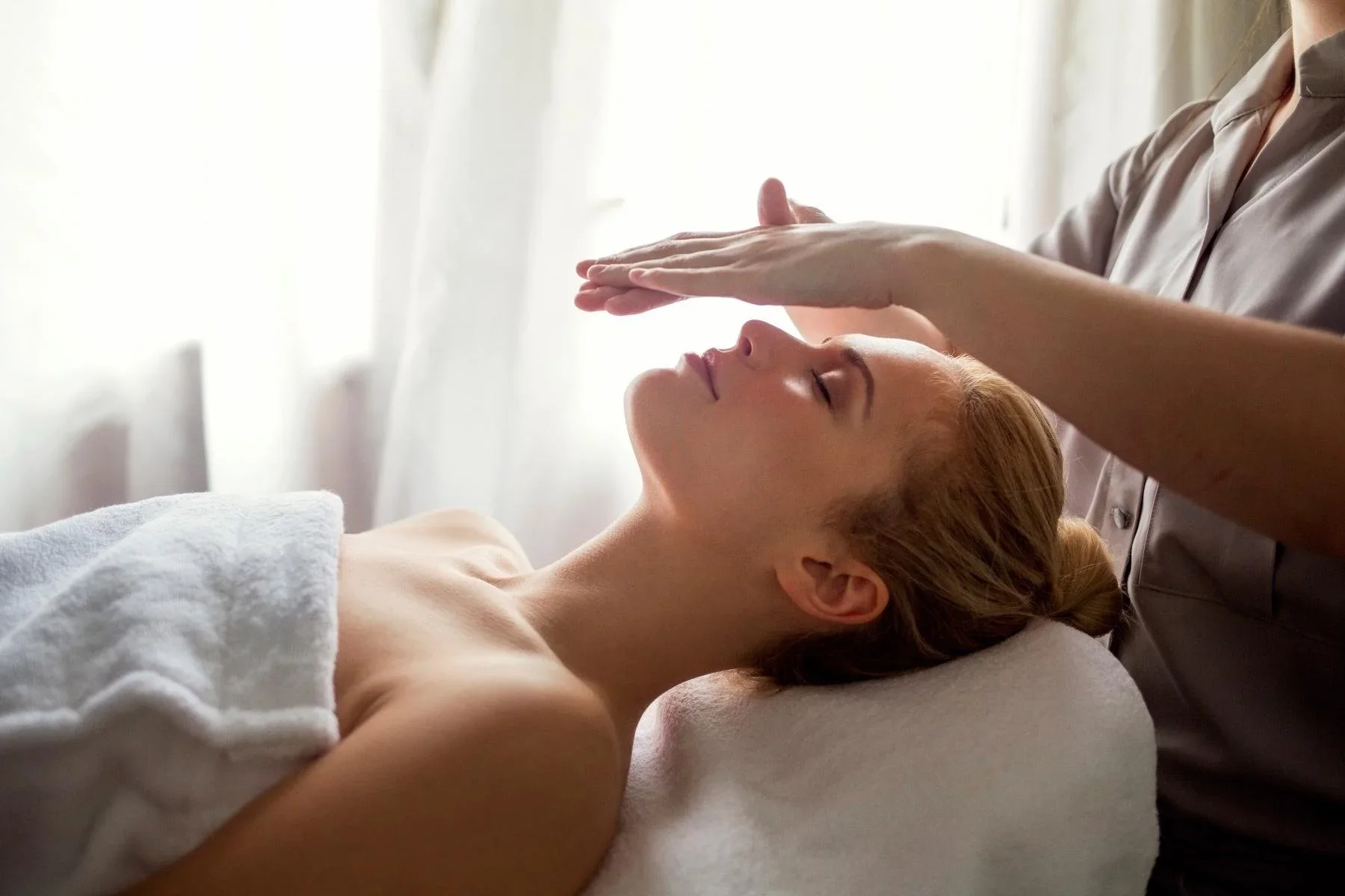 A woman receiving Reiki and light massage in a spa or wellness clinic.