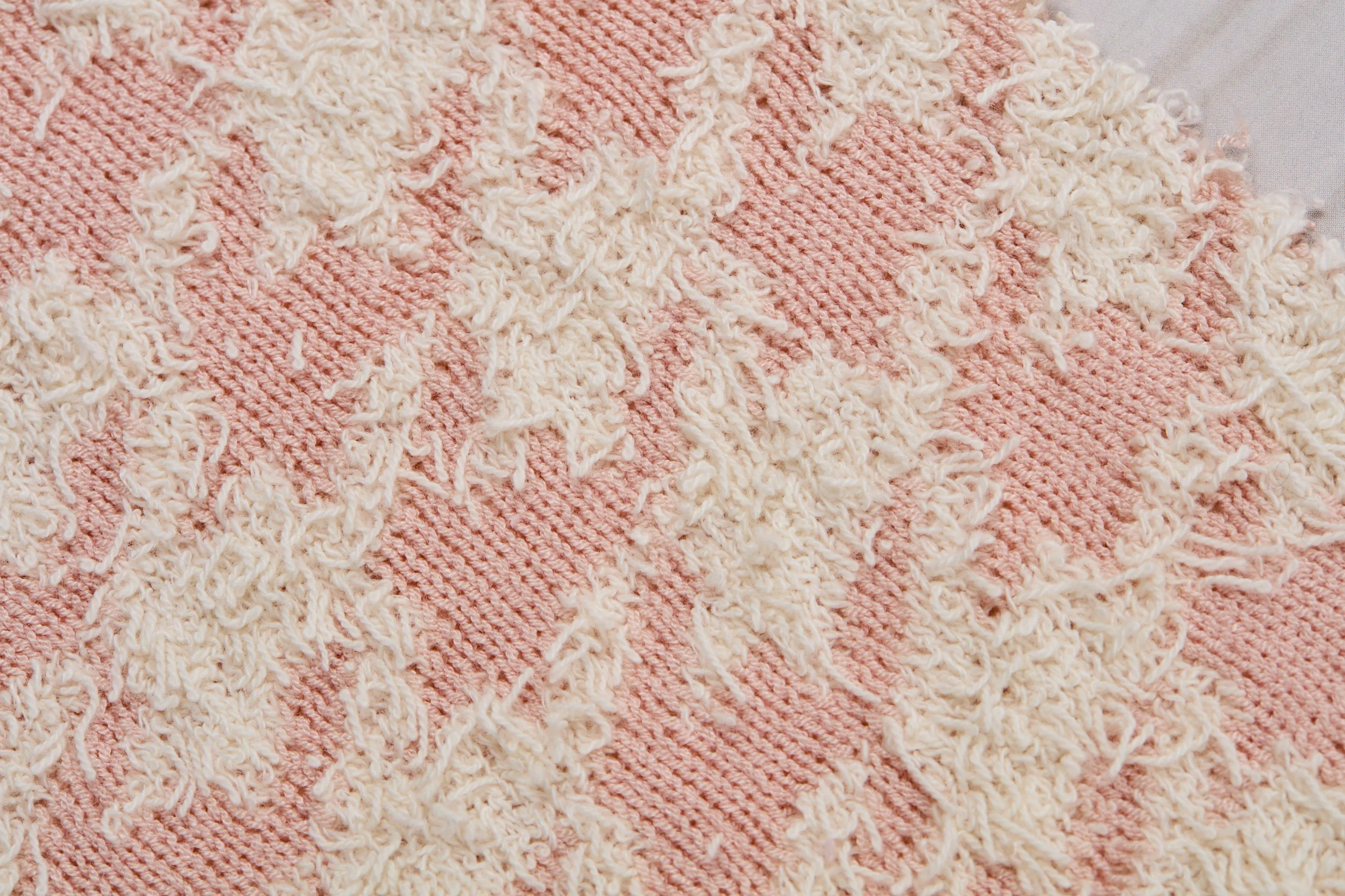 Tecido de tricô de cor rosa claro com detalhes em pontilhado na textura.