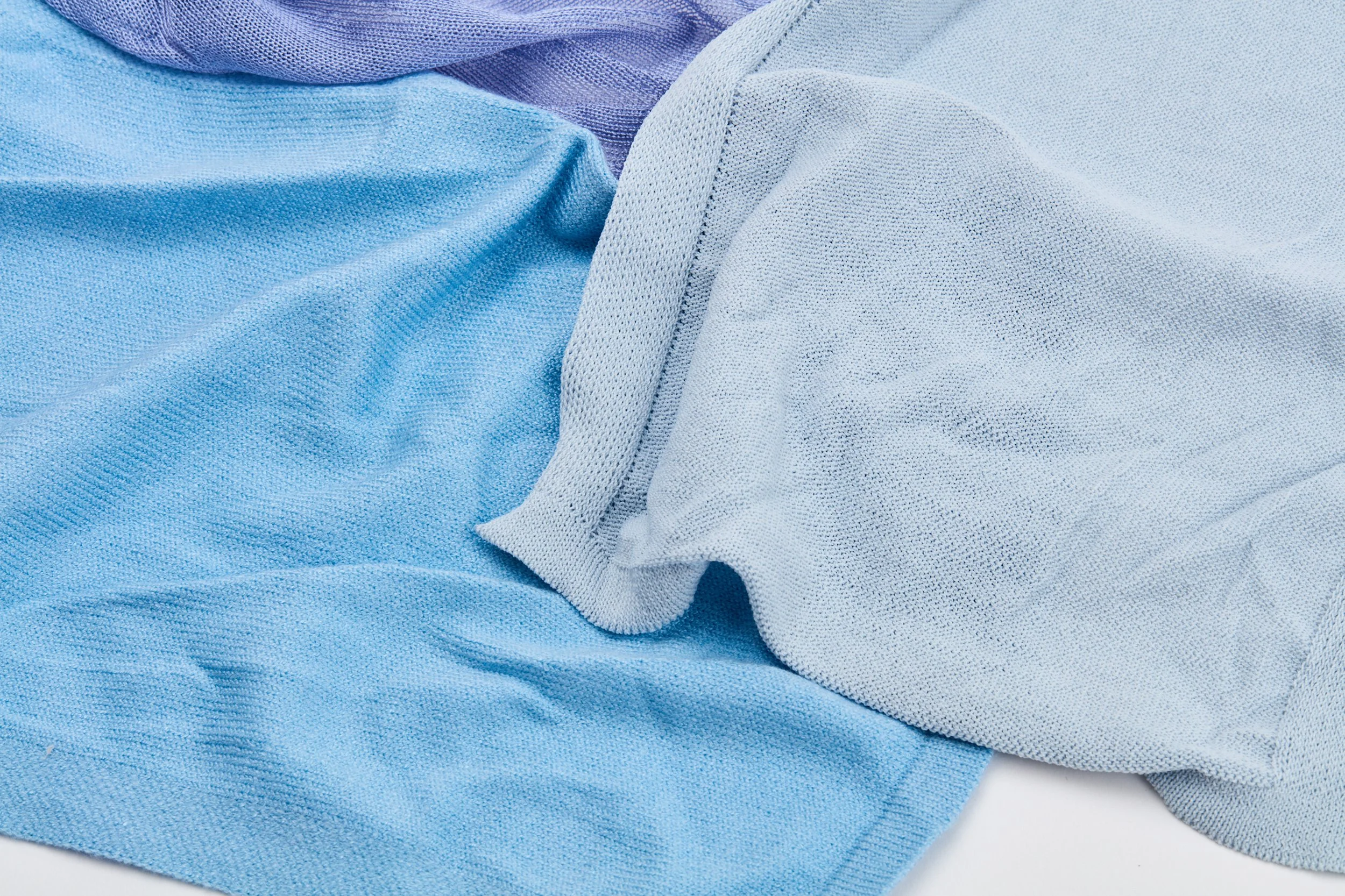 Toalhas de roupa em várias tonalidades de azul, arrumados e dobrados, com tecido de algodão visível.