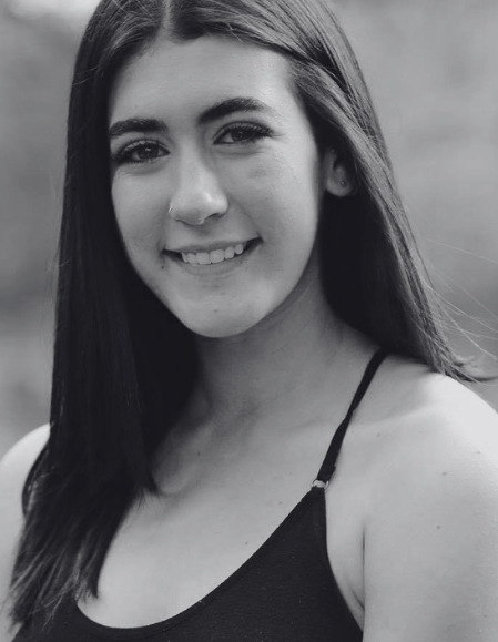Black-and-white portrait of a young woman smiling, wearing a sleeveless top.