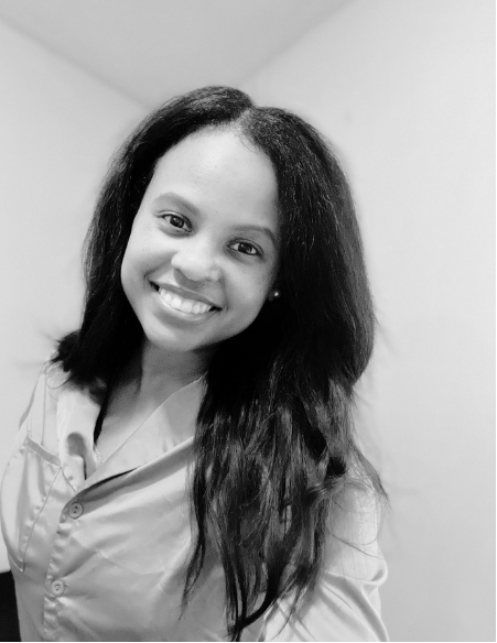 A young woman smiling with long, dark hair, wearing a collared shirt, in a black-and-white photo.