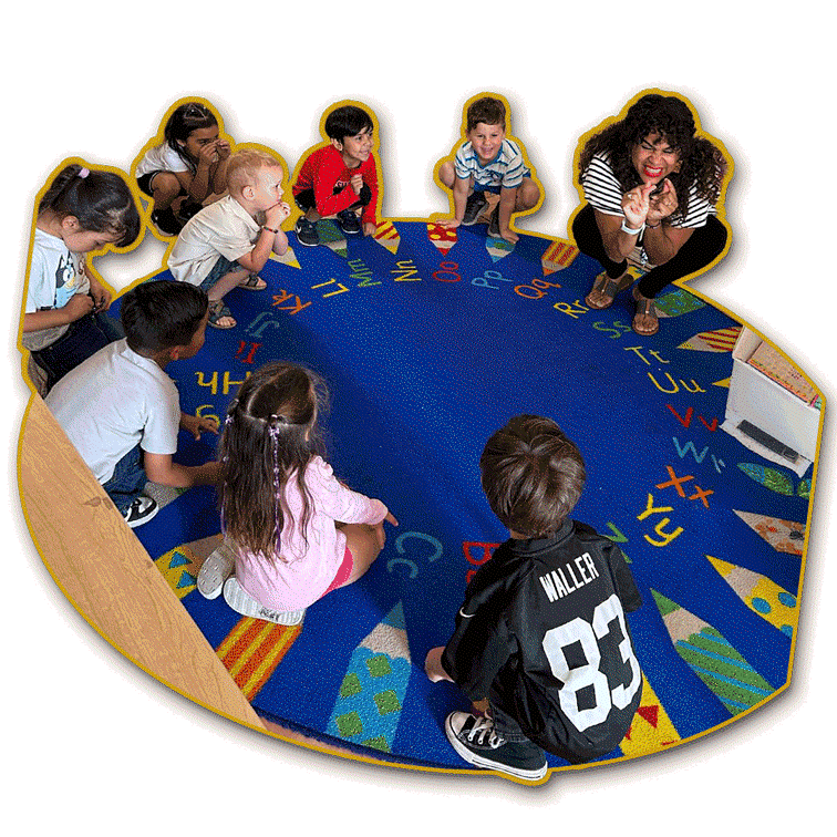 Group of children sitting in a circle on a colorful alphabet-themed rug in a classroom, with a female teacher engaging with them.